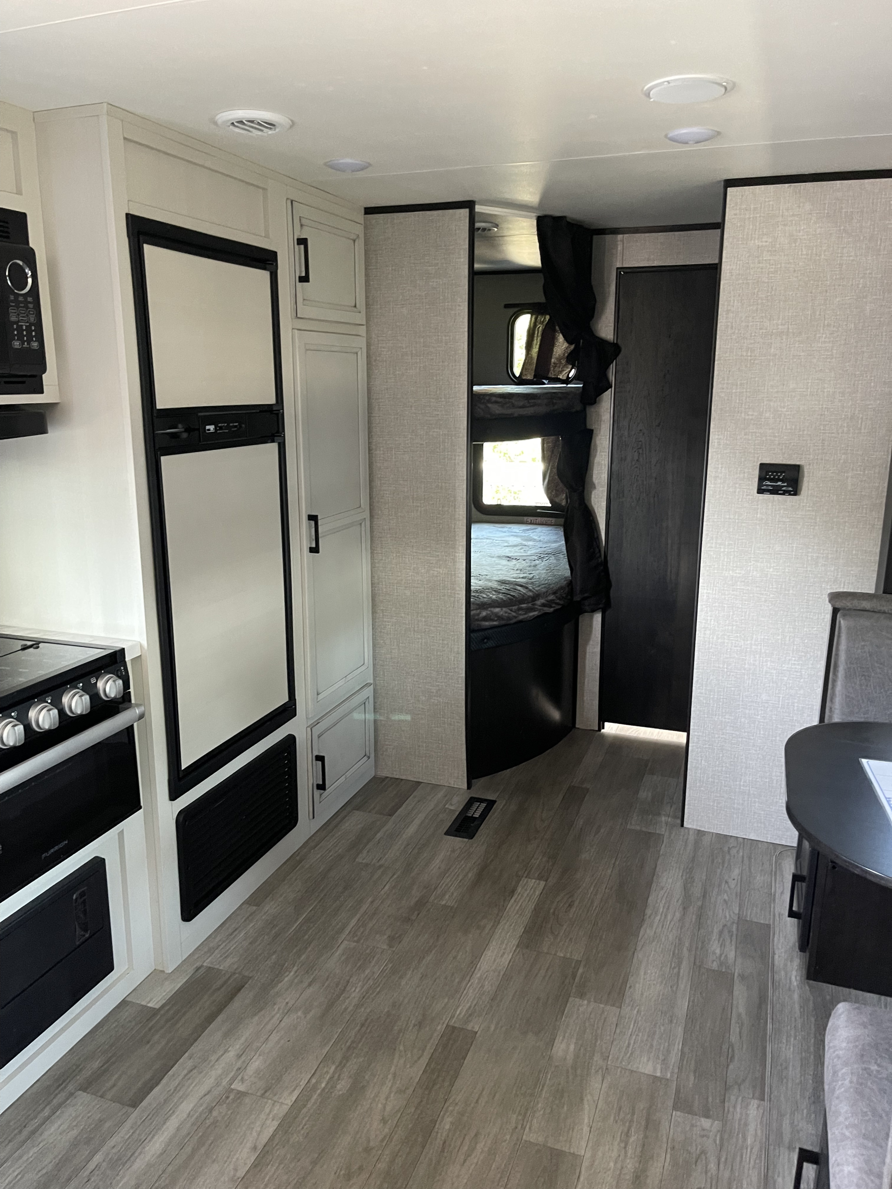 An RV rental interior with a kitchen (fridge, oven, microwave), bunk beds, and dining nook, showcasing efficient mobile living.. Jayco Jay Flight SLX 2022