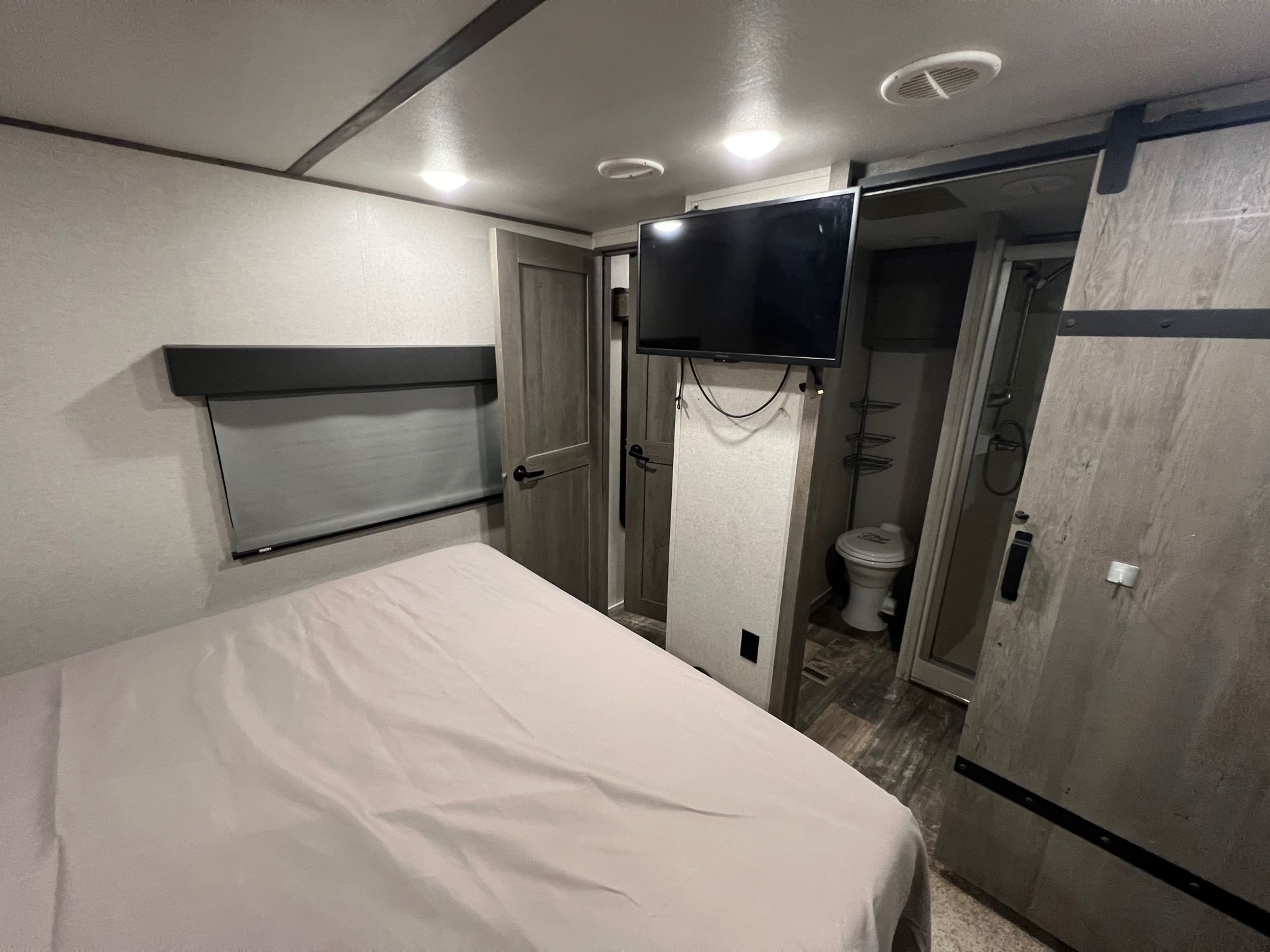 RV rental: Bedroom with bed, mounted TV, and visible en-suite bathroom with toilet and shower stall.. Keystone RV Raptor Toy Hauler 2020