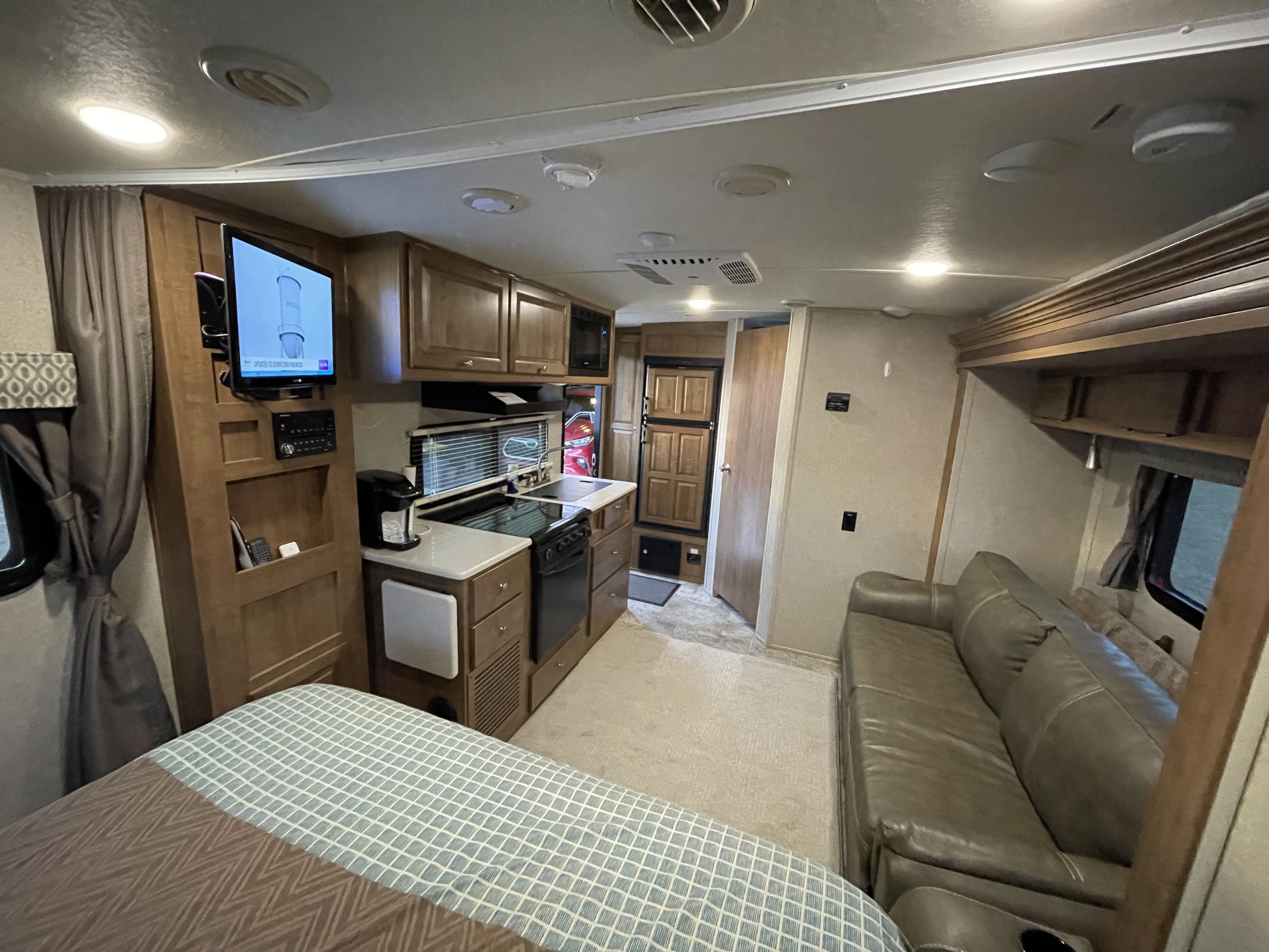 Comfortable RV rental interior: a cozy bed, full kitchen with appliances, and spacious living area with a sofa.. Forest River Flagstaff Micro Lite 2017