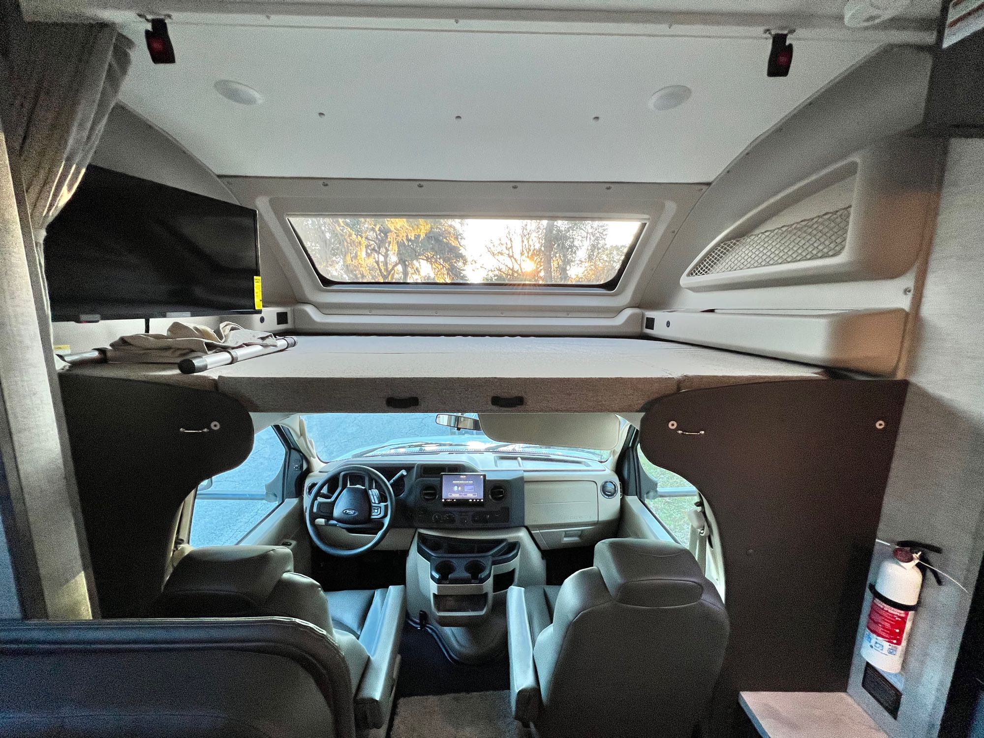 Cozy RV rental interior: cab-over bunk, TV, and cockpit view. Ready for your next road trip adventure!. Entegra Coach Odyssey 2023