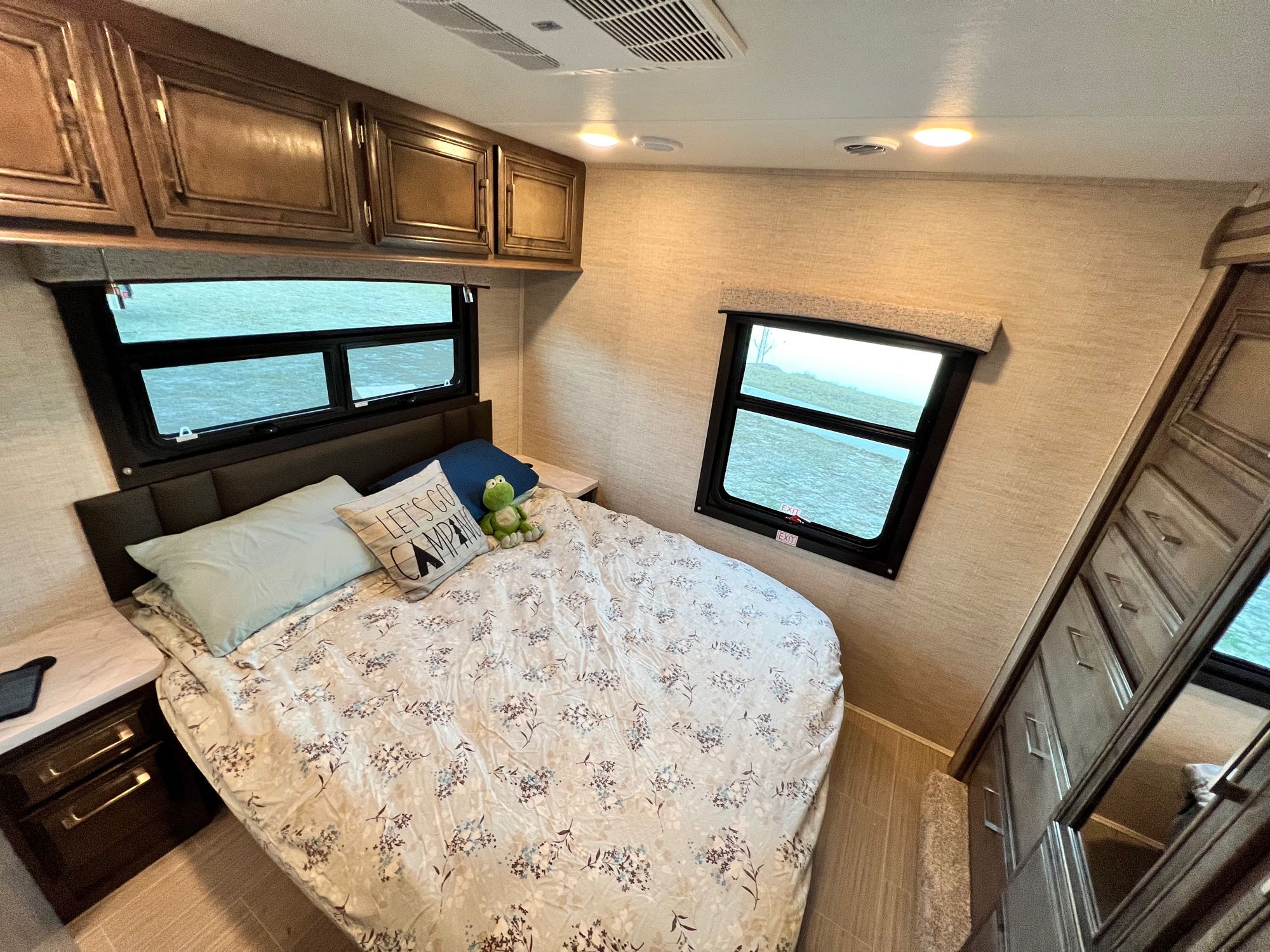 Cozy RV rental bedroom with floral bedding, ample storage, and scenic window views for comfortable camping trips.. Entegra Coach Odyssey 2023