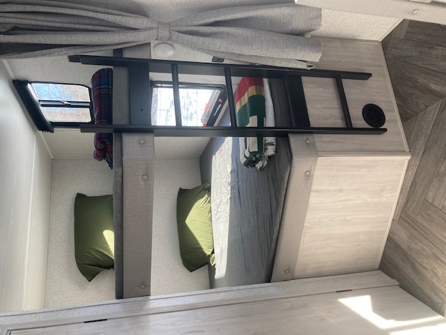 RV rental interior: bunk beds with a ladder, green pillows, and windows. Great for a family adventure.. East to West Della Terra 2022