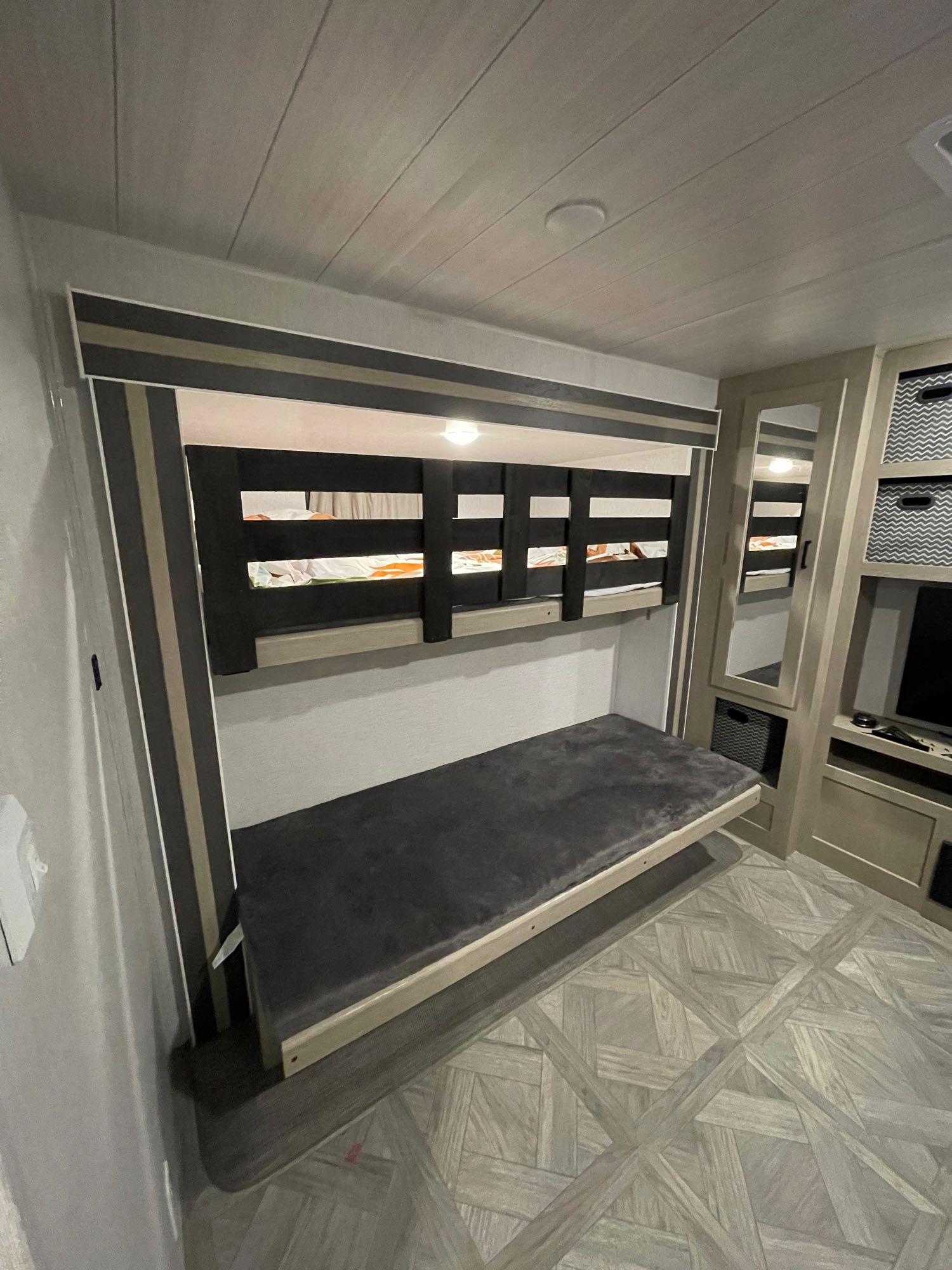 RV rental interior: A bright, compact bunk bed area with a lower fold-down bed and upper bunk, plus built-in storage.. Forest River Wildwood 2023