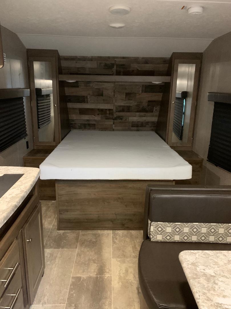 RV rental interior: compact bedroom with bed, side cabinets, plus adjacent dinette & kitchen. Cozy travel space.. Dutchmen Other 2019