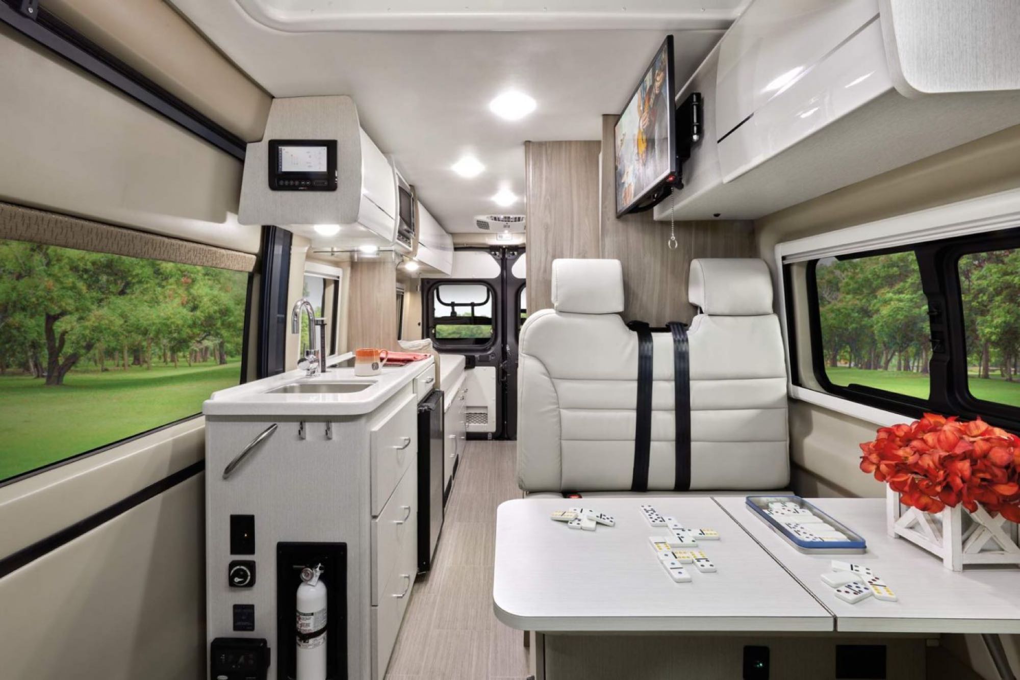RV rental interior: A bright, functional living space with kitchenette, seating, & table for games like dominoes. Green view outside.. Thor Motor Coach Tellero 2022