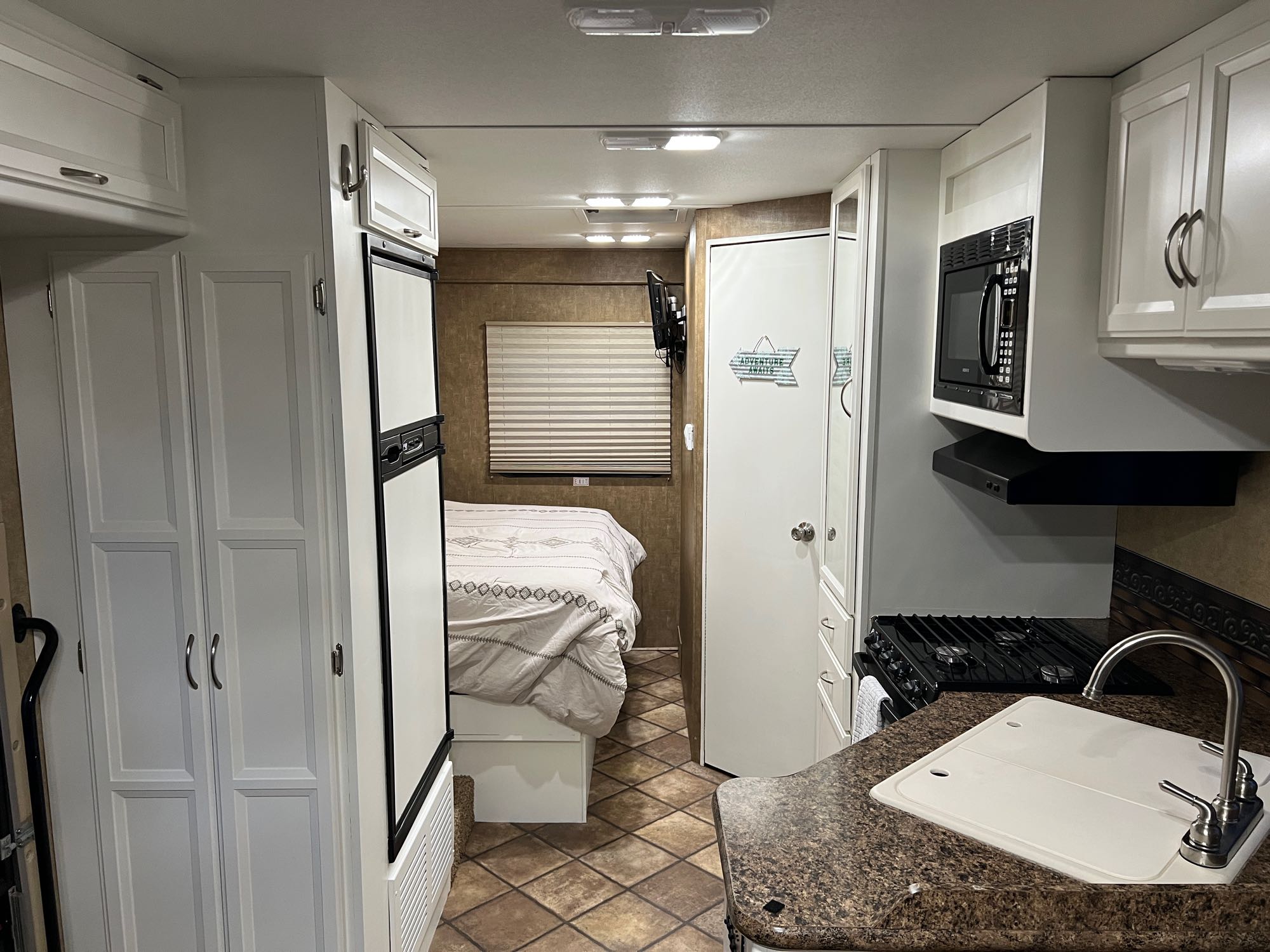 Clean rv rental interior showcasing a compact kitchen, comfortable bed area, and white cabinetry.. Thor Four Winds 2014