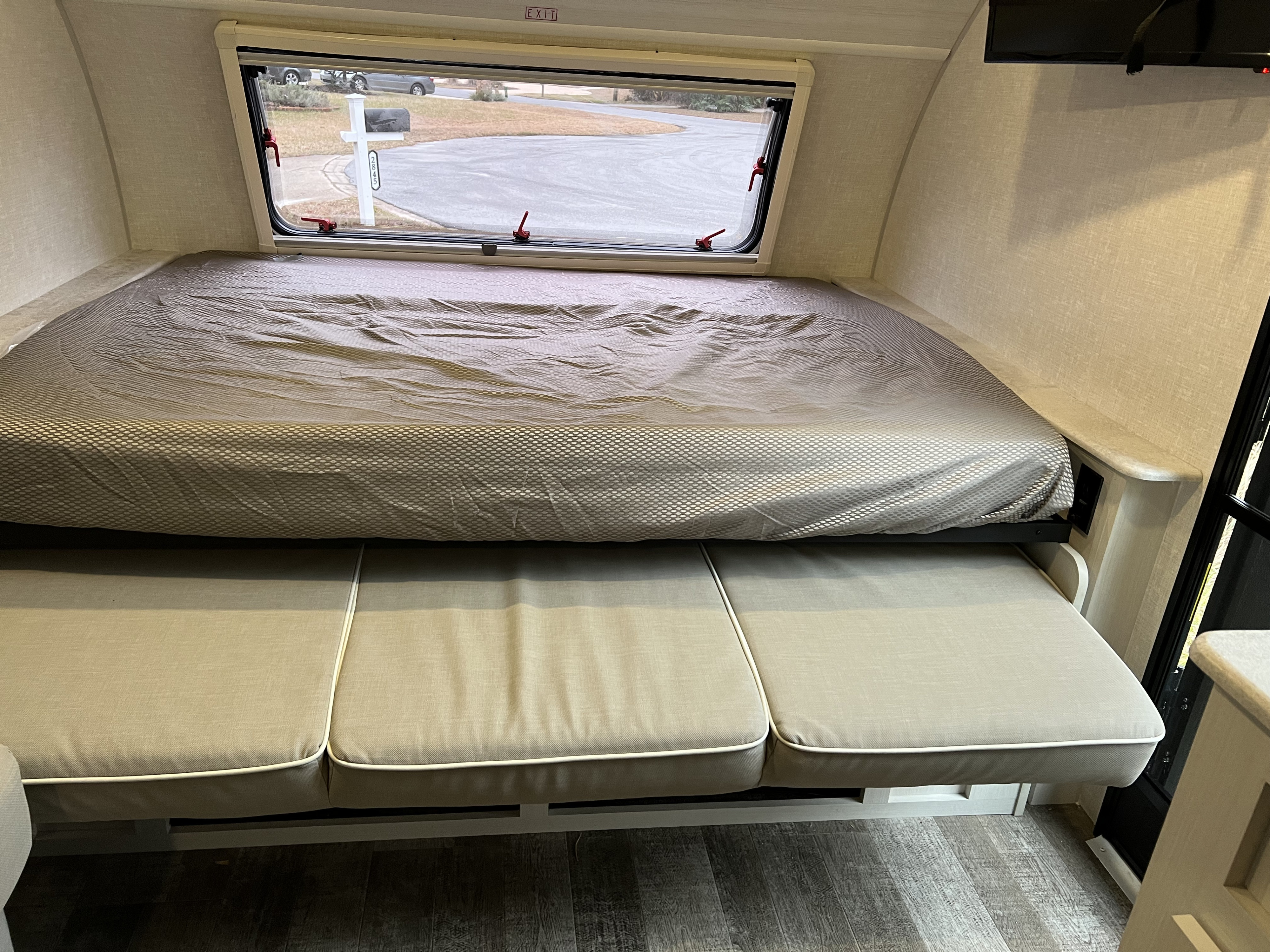 Compact RV rental interior featuring a bed, lower sofa seating, and window with an EXIT sign.. Forrest River R-Pod 193 2022