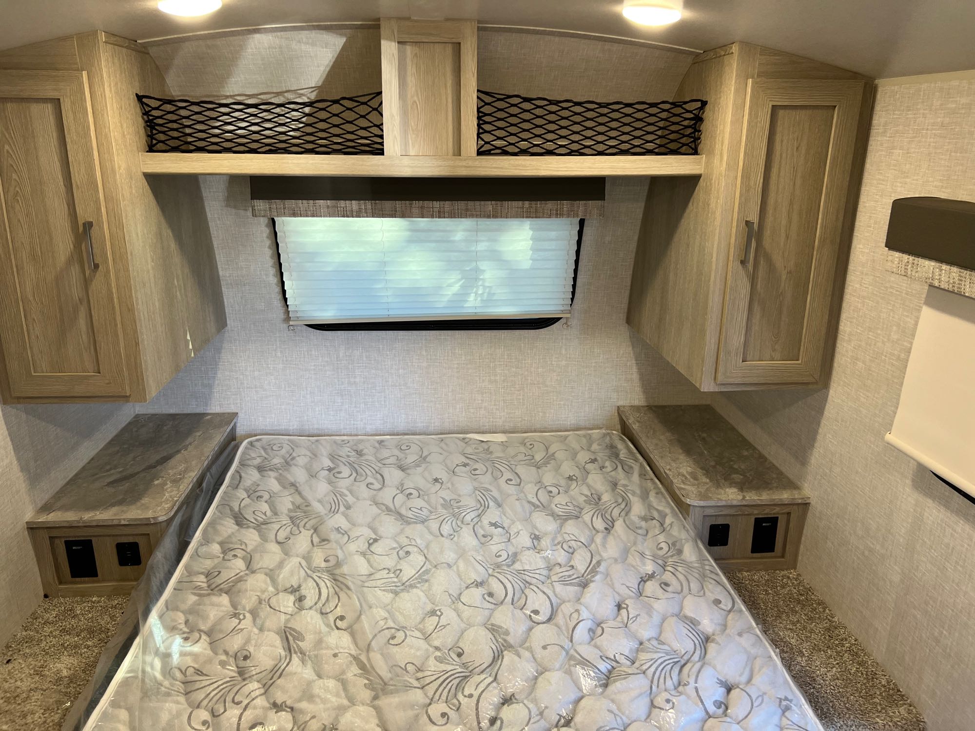 Cozy RV rental bedroom with queen bed, nightstands, overhead cabinets & storage nets. Ideal for travelers.. Forest River Flagstaff E-Pro 2022