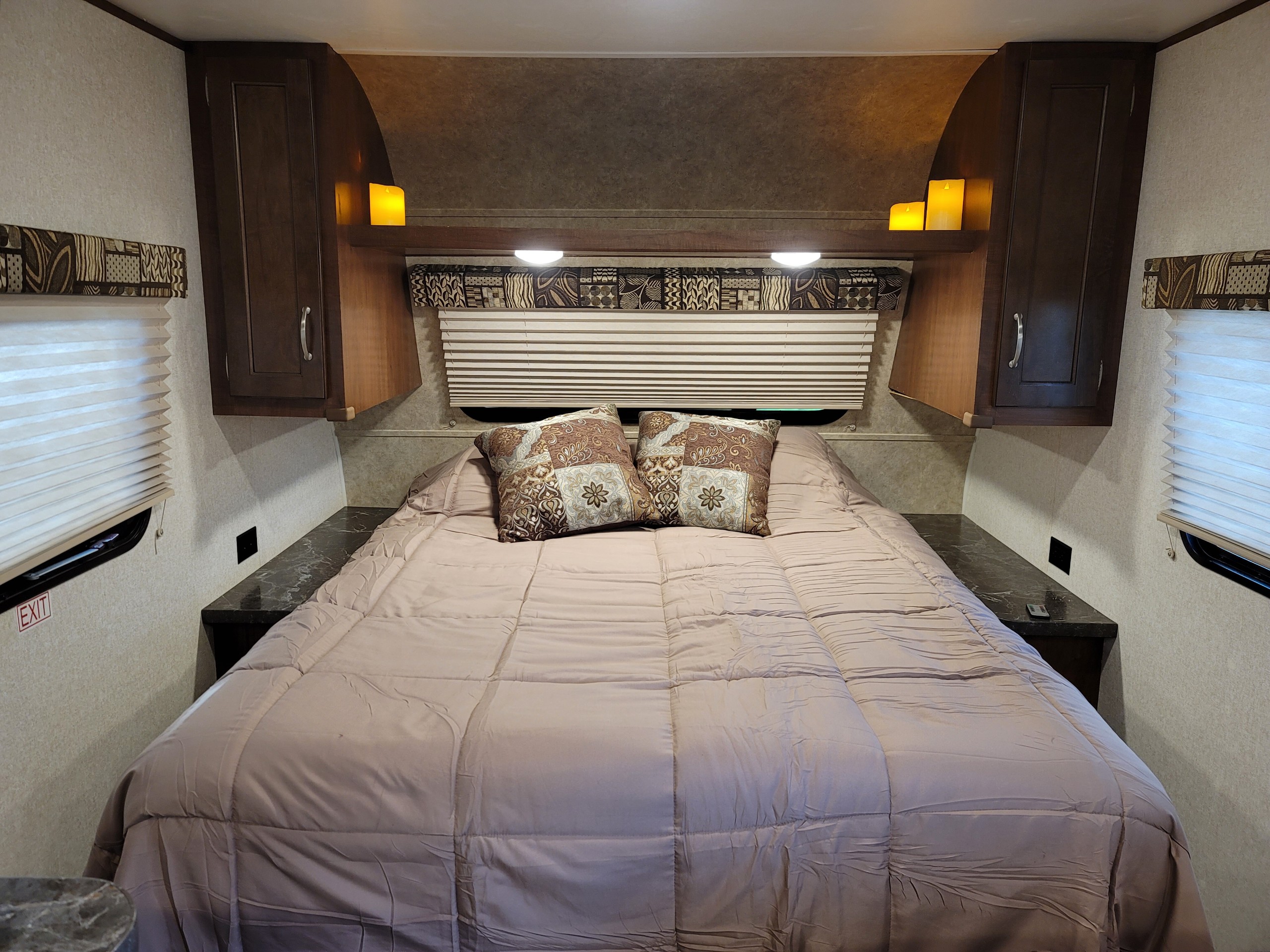 Cozy RV rental bedroom with a comfy bed, patterned pillows, overhead cabinets, and soft ambient lighting for a relaxing stay.. Jayco Jay Flight 2017