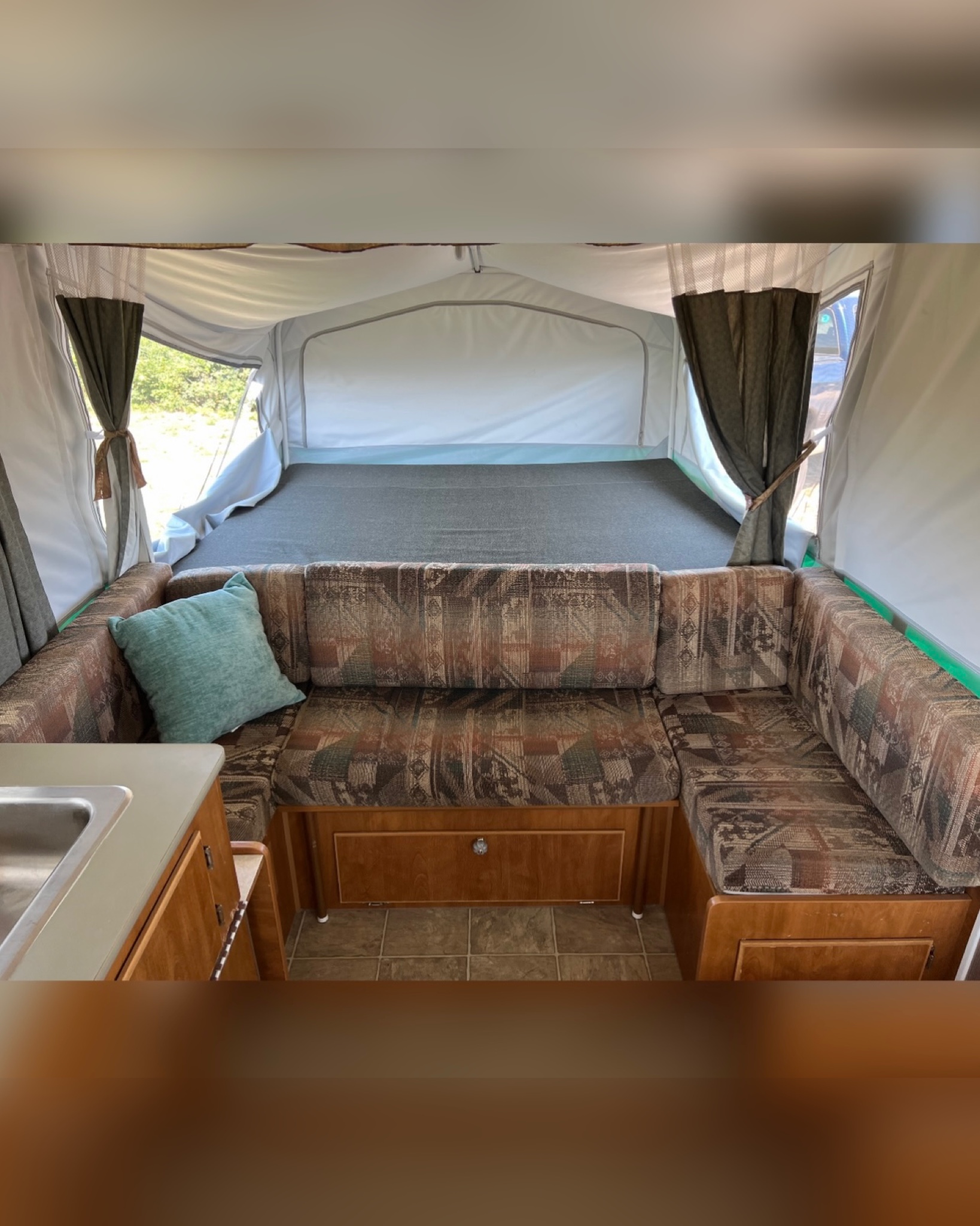 Cozy RV rental interior featuring a patterned dinette, a large bed area, and a compact sink. Ready for adventure!. Other Other 2005