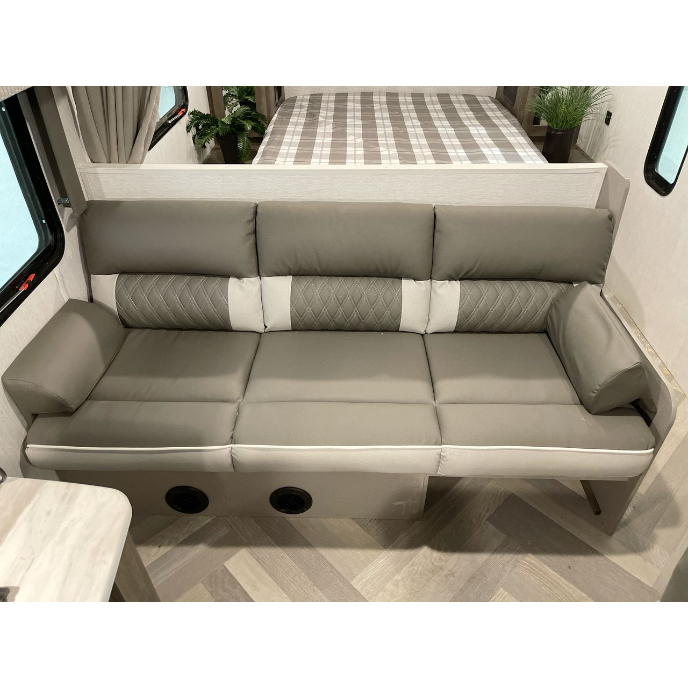 Experience this RV rental interior: a sleek gray sofa and bed area with modern touches. Your adventure awaits!. Forest River Wildwood X-Lite 2022