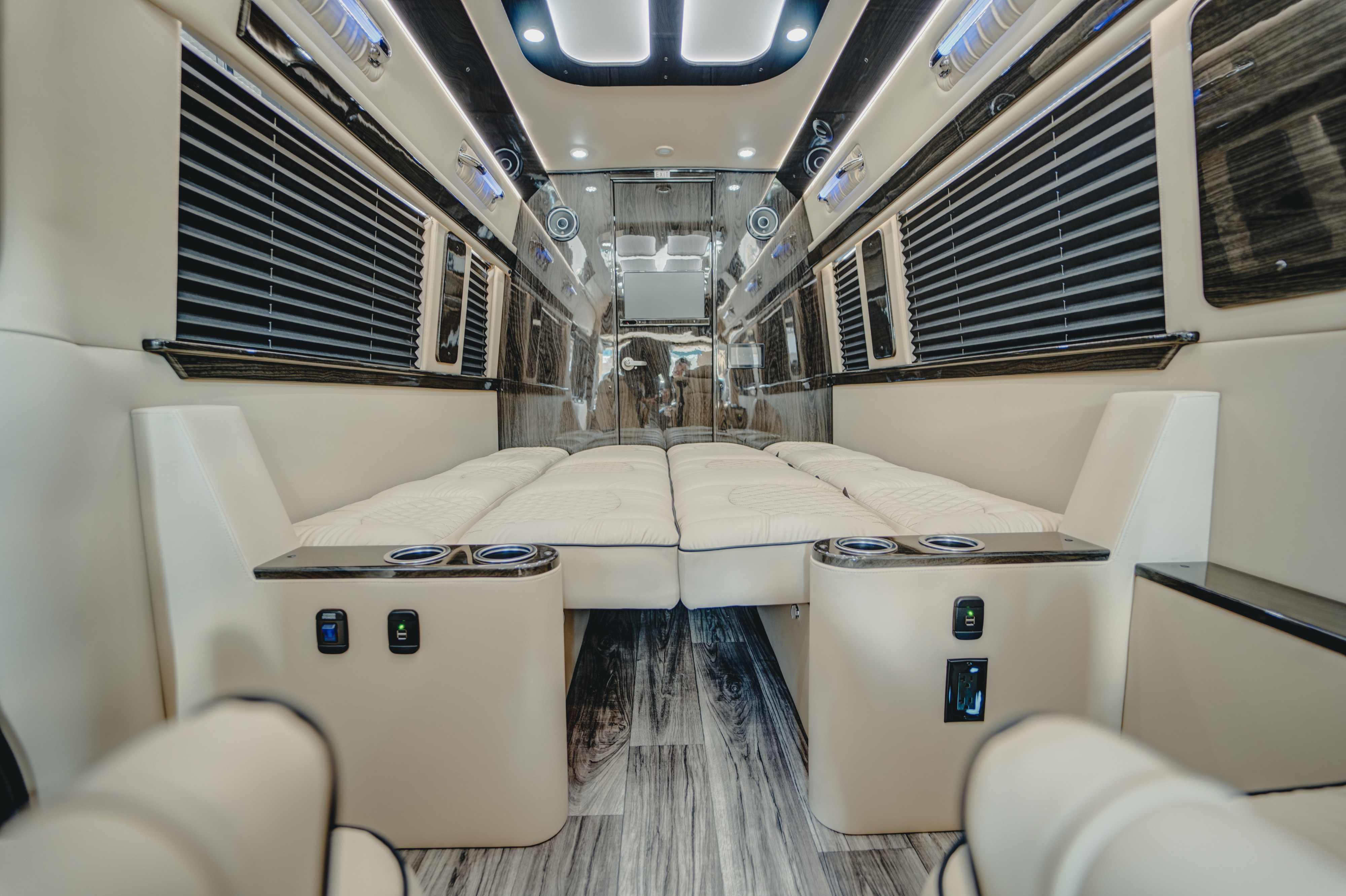 Luxury RV rental interior: view of a spacious bedroom with two plush cream-colored beds, dark wood paneling, and cupholders.. Ultimate Toys Ultimate Traveler 2023