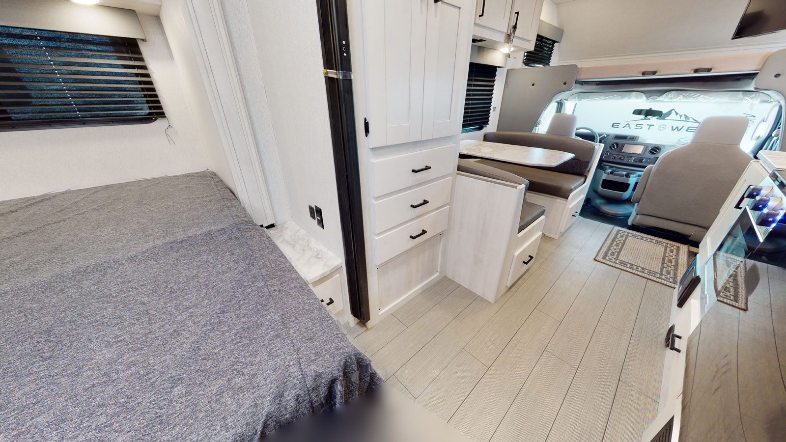 Spacious rv rental interior featuring a cozy bedroom, dinette, and cockpit area with light wood finishes.. Forest River Entrada 2022