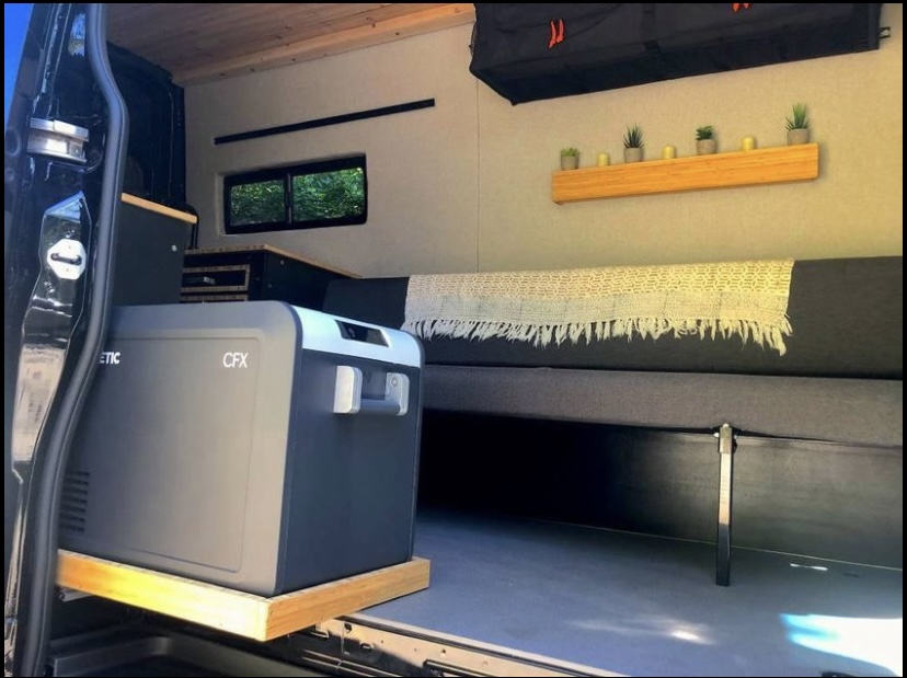 Inside a custom RV rental: Dometic CFX portable fridge, comfy bed, and decor shelf. Ideal for mobile van living adventures.. Mercedes Sprinter 2021