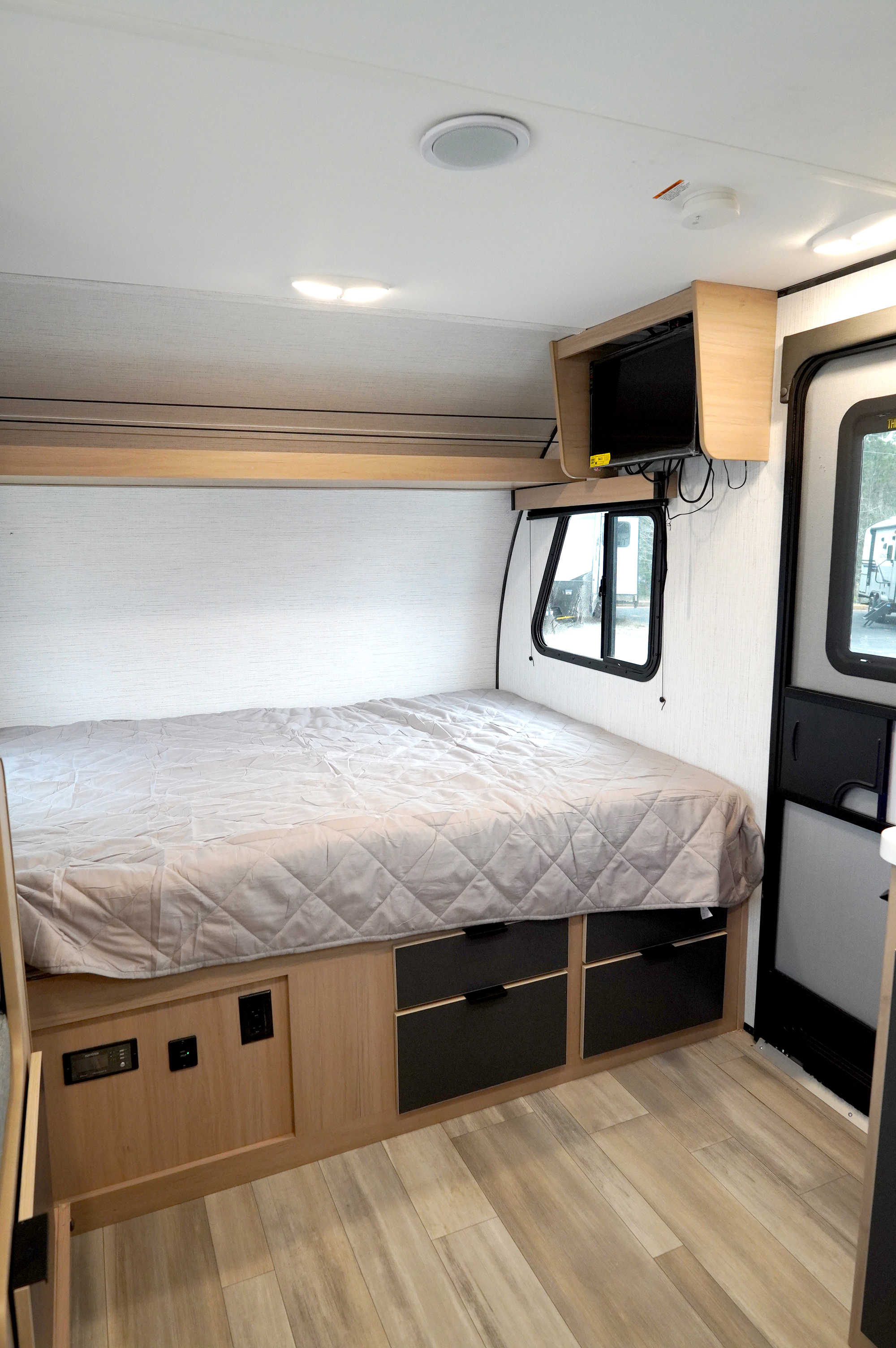 RV rental interior: Comfortable bedroom featuring a bed, mounted TV, storage drawers, and light wood flooring.. Cruiser Rv Corp Hitch 2022