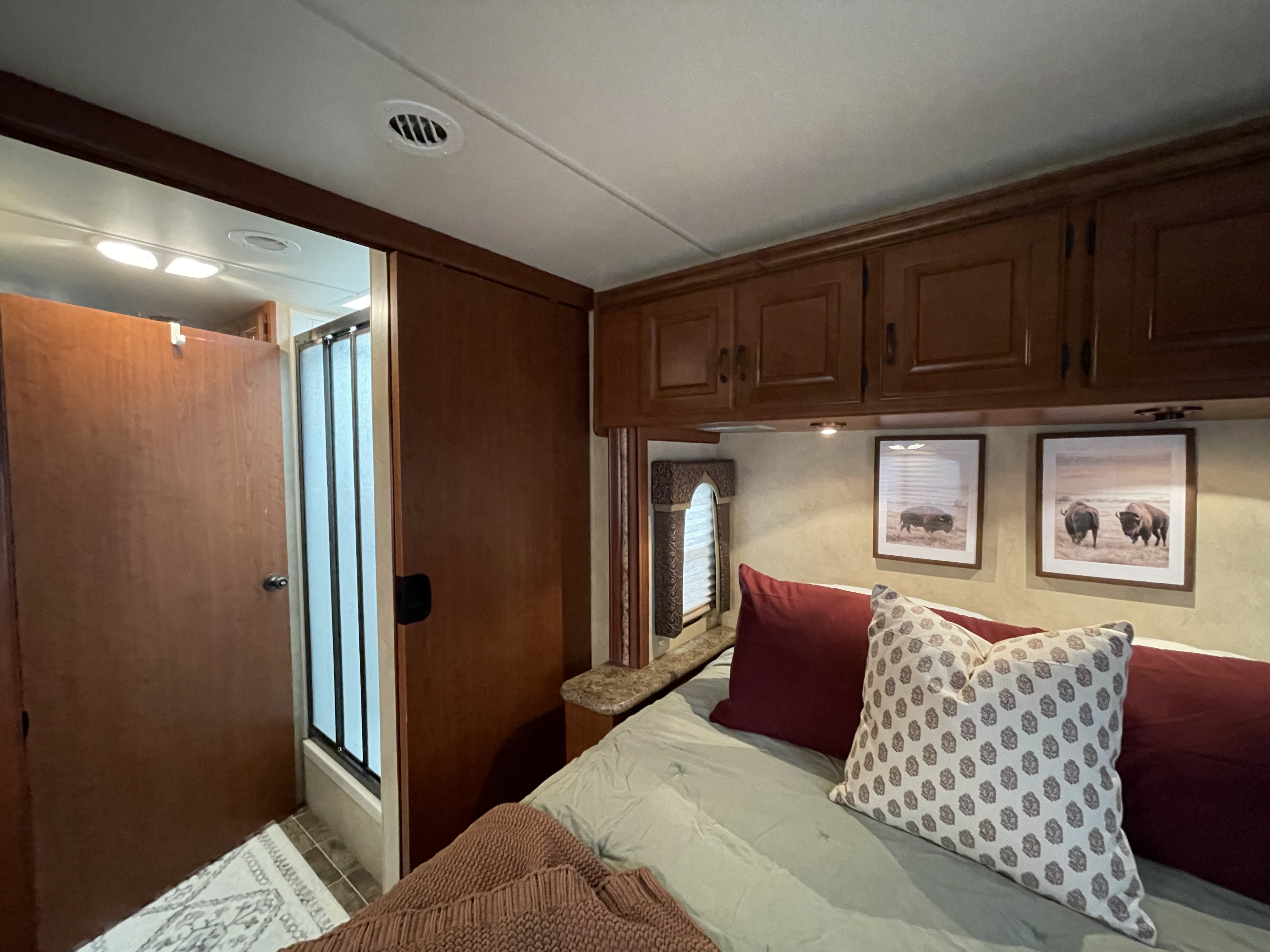 Inside an inviting RV rental bedroom: a comfortable bed, cabinets, and a practical shower area for your next adventure.. Thor Hurricane 2012