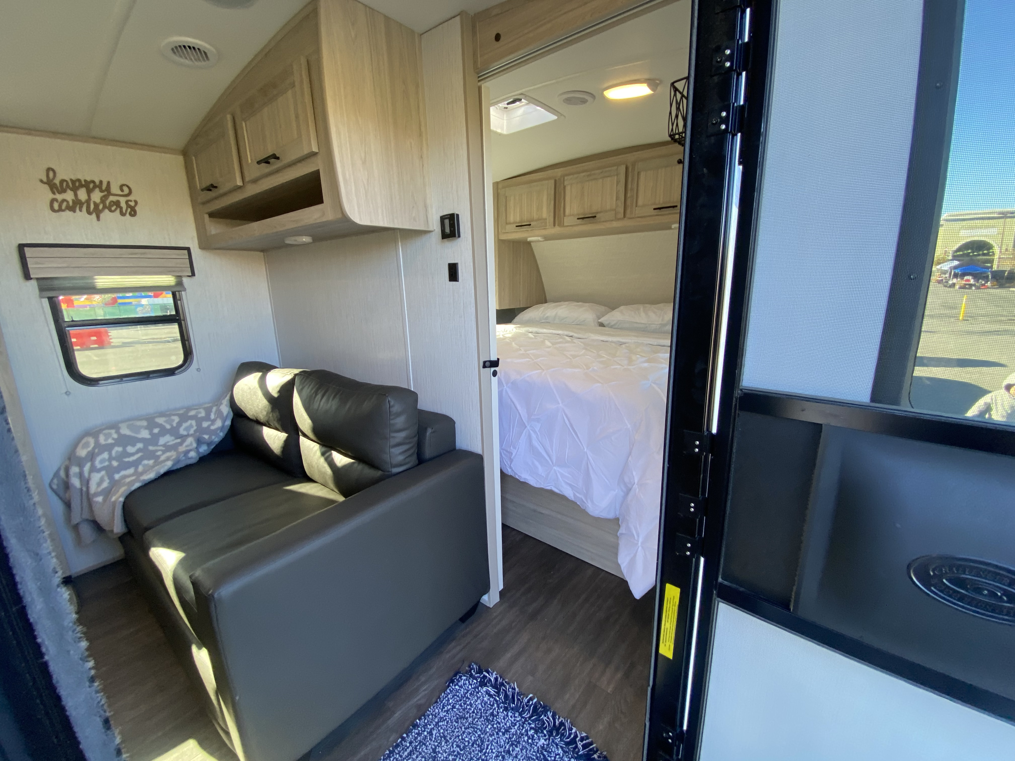 Step inside this bright RV rental, featuring a living area with a sofa and a cozy bedroom beyond.. Cruiser RV Shadow Cruiser 2022