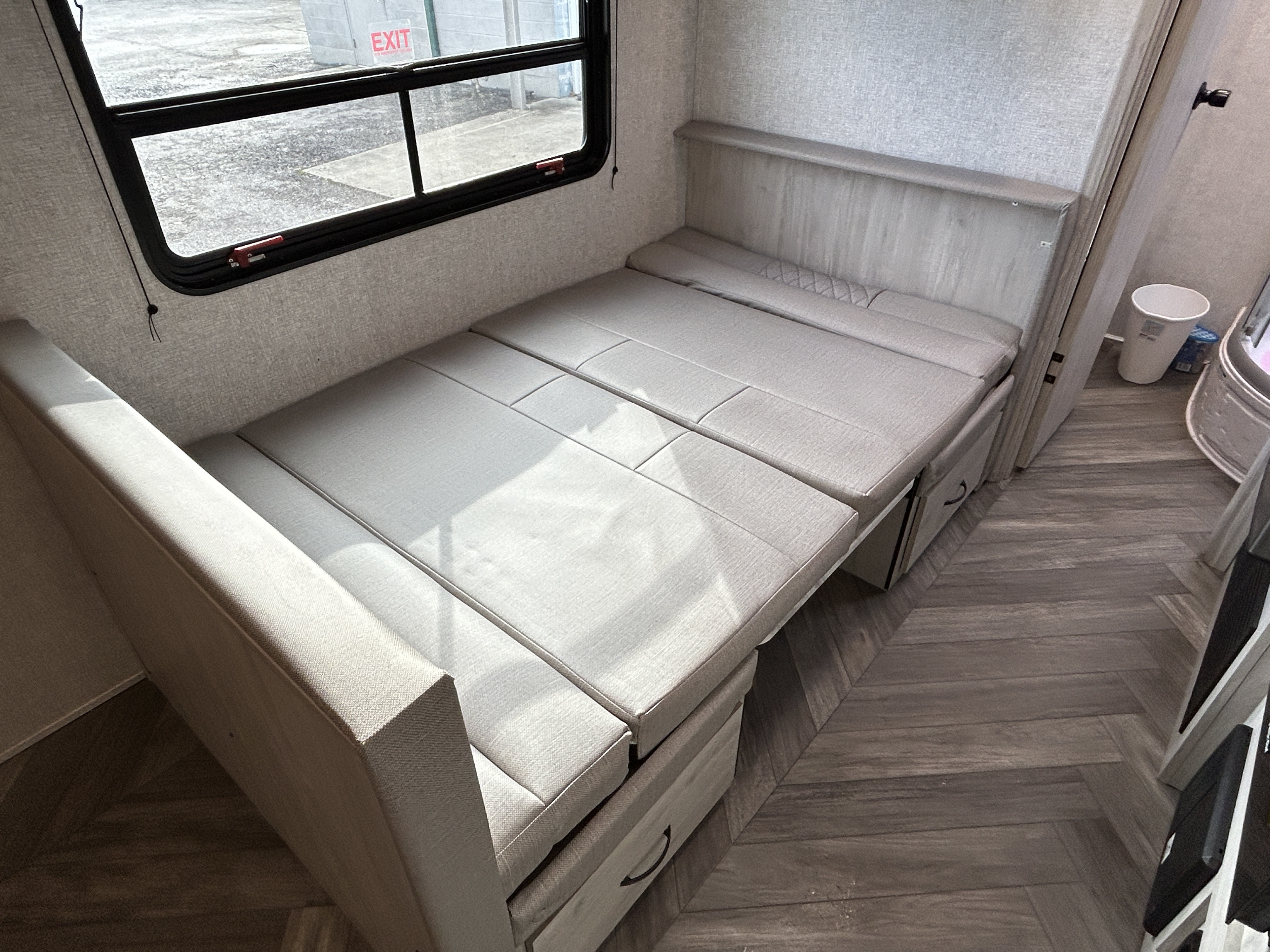RV rental interior with a versatile dinette that converts into a comfortable bed, featuring under-seat storage and a large window.. East to West Della Terra 2022