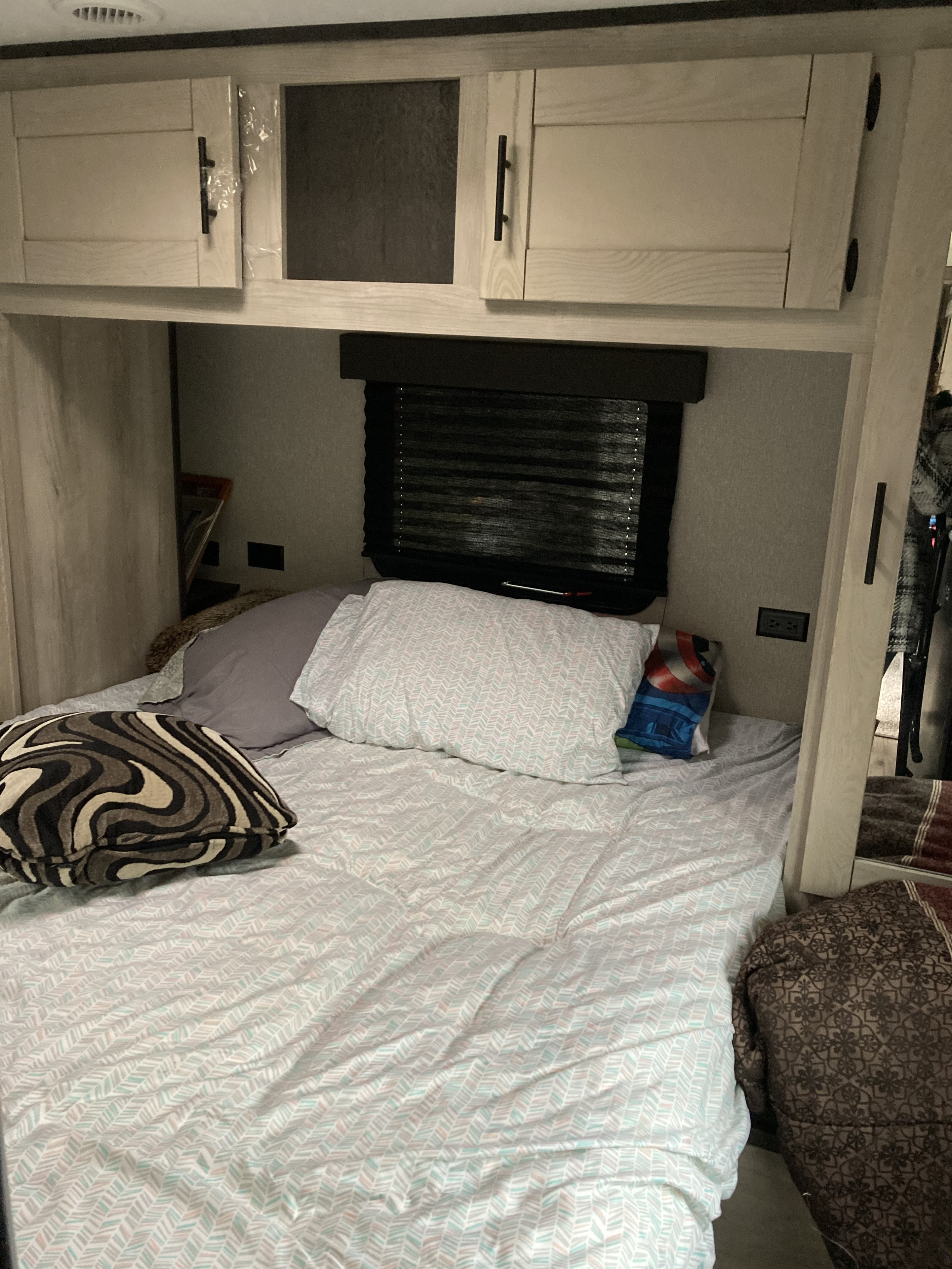 Inside a comfy RV rental bedroom: light-colored bedding, overhead cabinets, and window blinds. Perfect for travel.. KZ Connect 2021