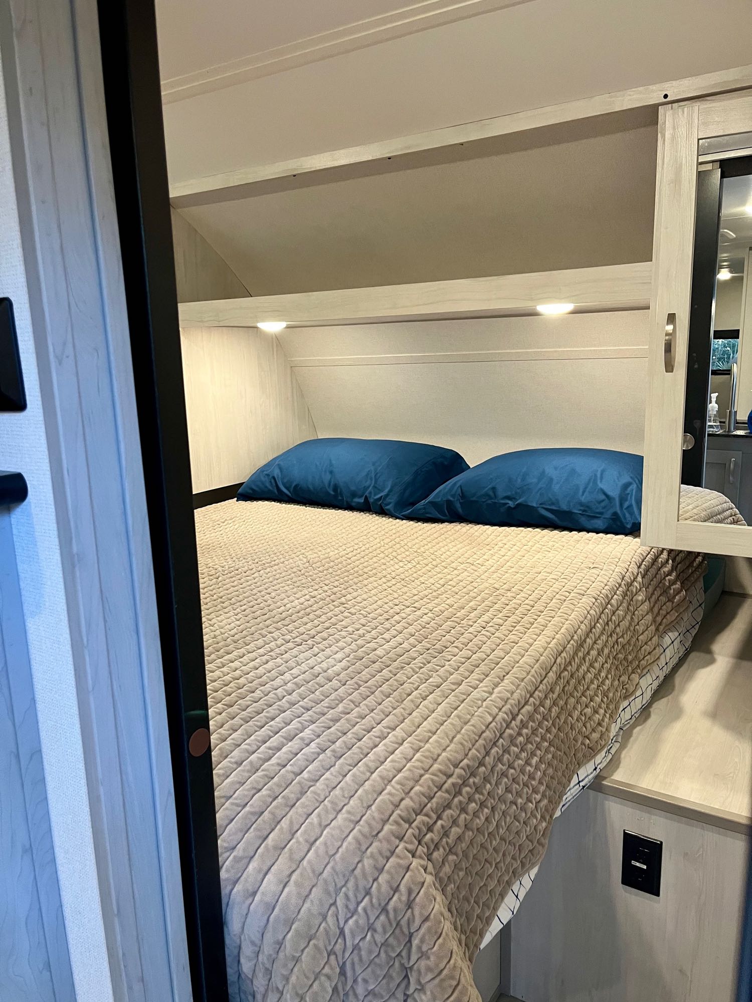 Cozy RV rental bedroom with a comfy bed, blue pillows, and built-in storage. Ideal for travel.. Forest River Tracer 2022