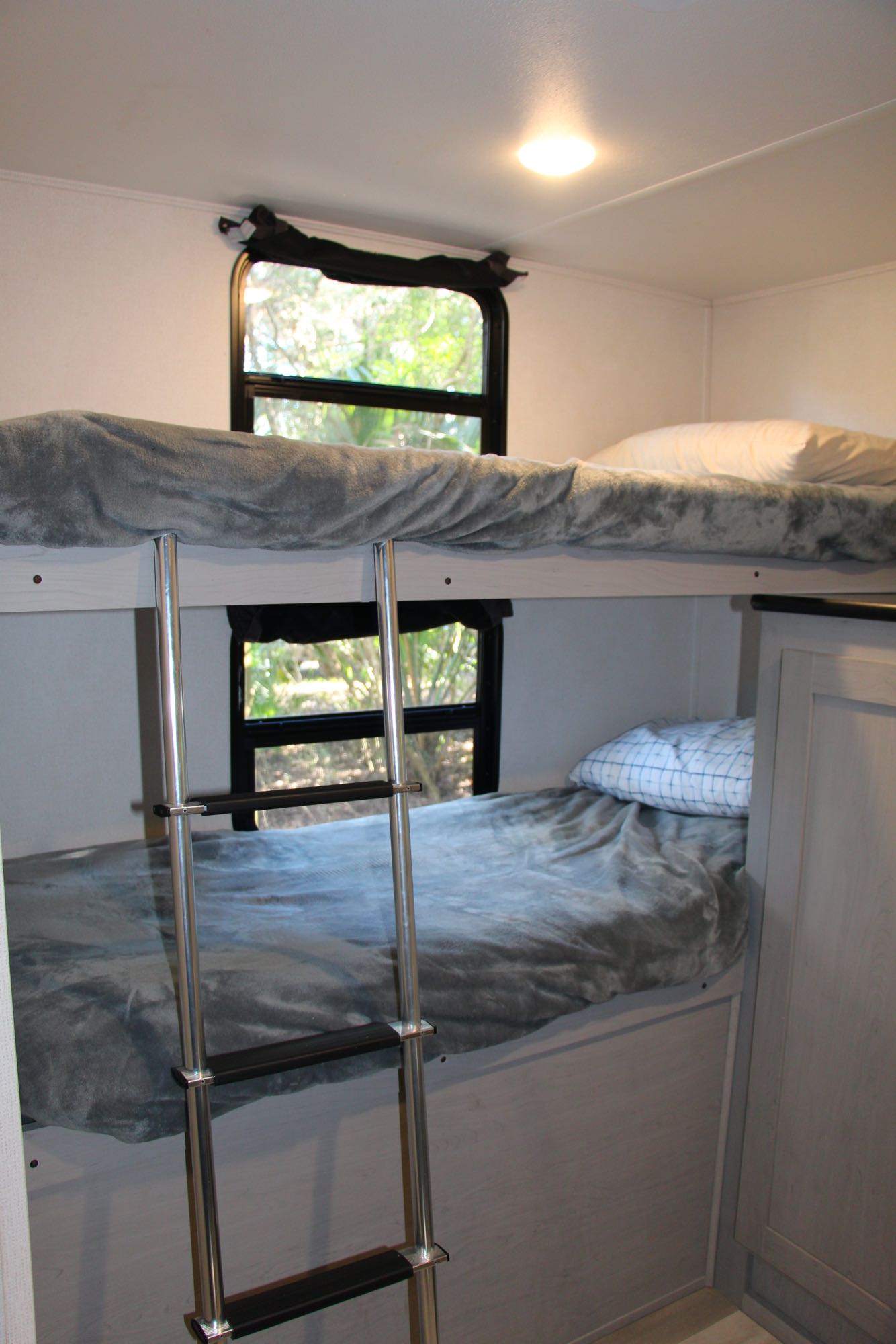 Cozy bunk beds inside an RV rental, featuring a ladder, comfortable bedding, and natural light from the windows.. Forest River Tracer 2022