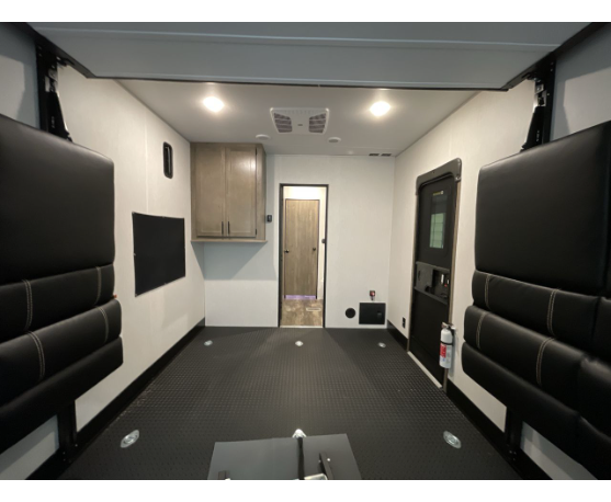 Spacious RV rental toy hauler garage, showing durable black floor, overhead beds/couches, and rear storage cabinets.. Forest River Cherokee Wolf Pack 2022