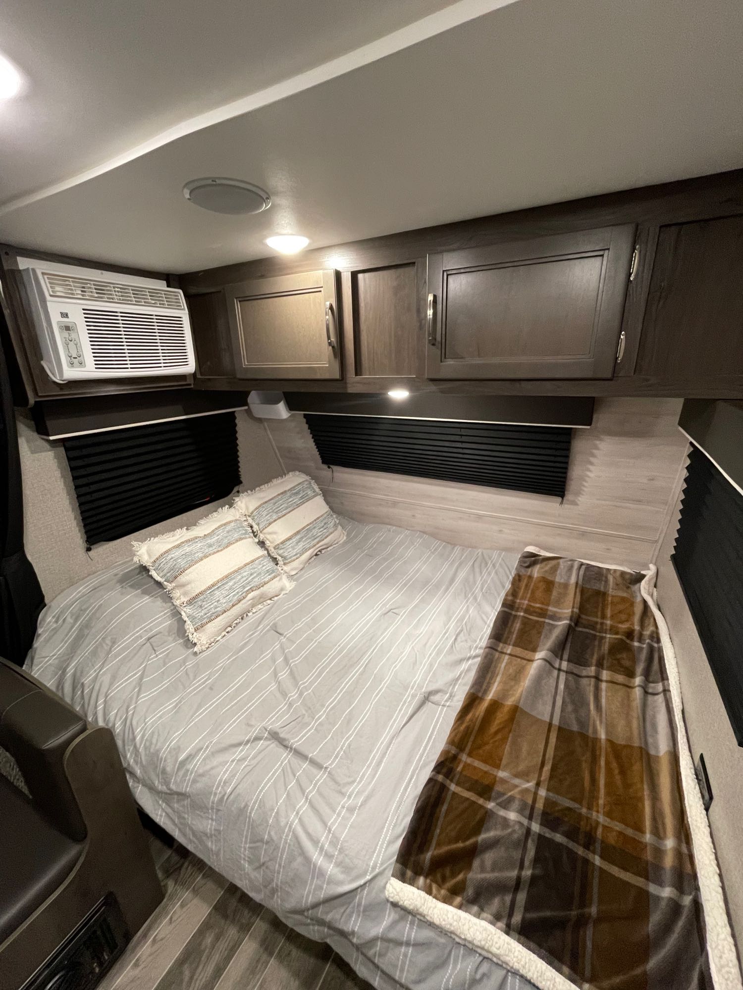 Cozy RV rental bedroom features a striped bed, plush blanket, AC, and storage cabinets for comfortable travels.. Jayco Jay Flight SLX 2021