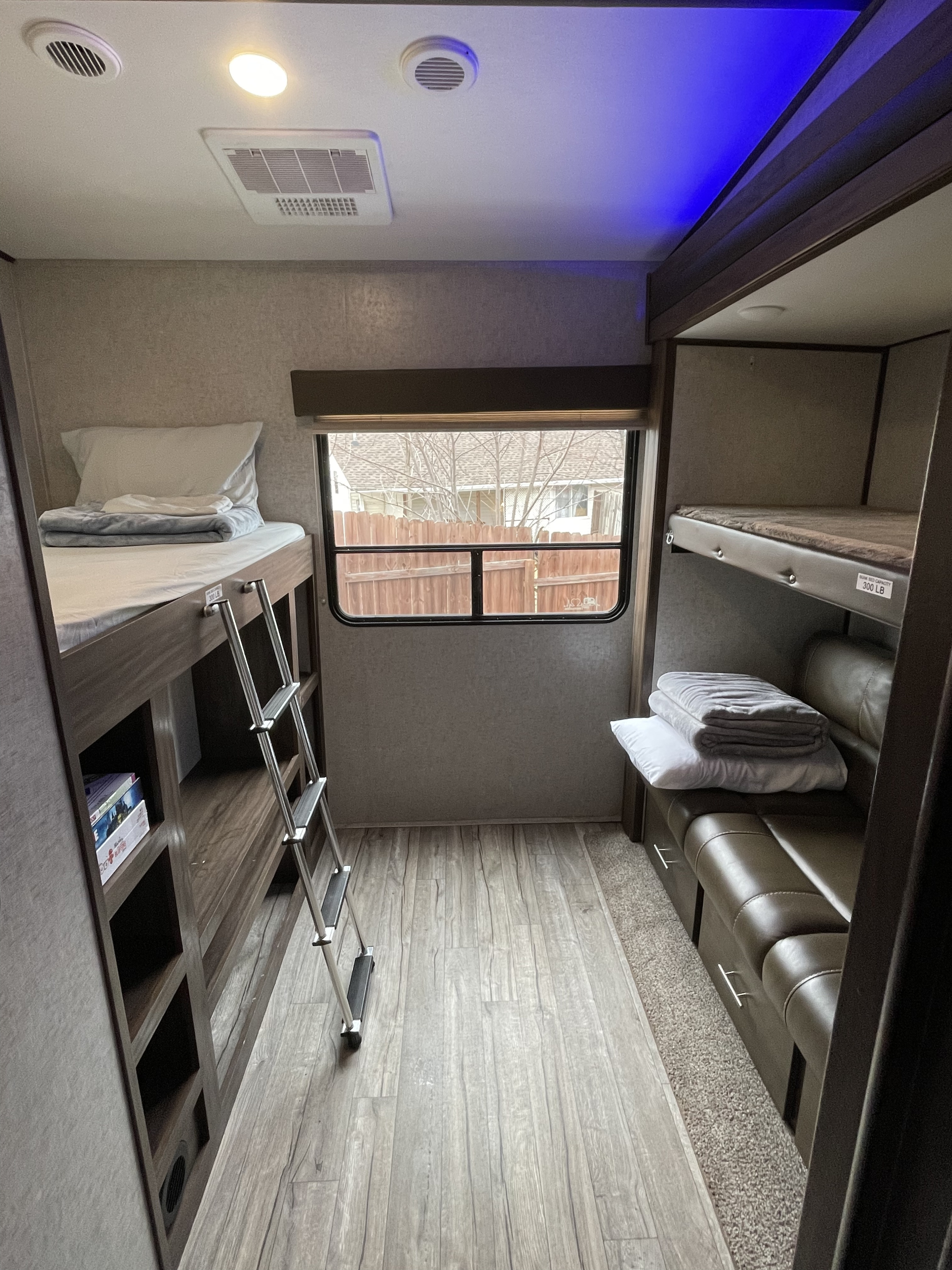 Spacious bunkhouse in this RV rental, with multiple beds, a ladder, window view, and seating area.. Forest River Cherokee Arctic Wolf 2018