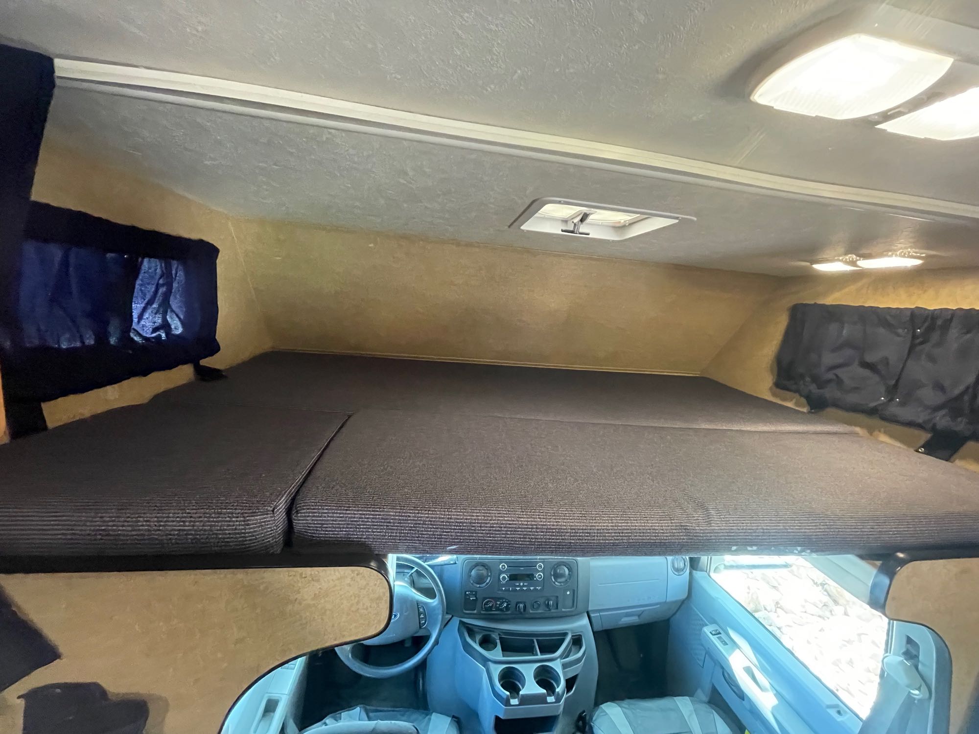 Inside this RV rental, view the large cab-over bunk bed situated above the vehicle's dashboard and front seats.. Thor Majestic 2018