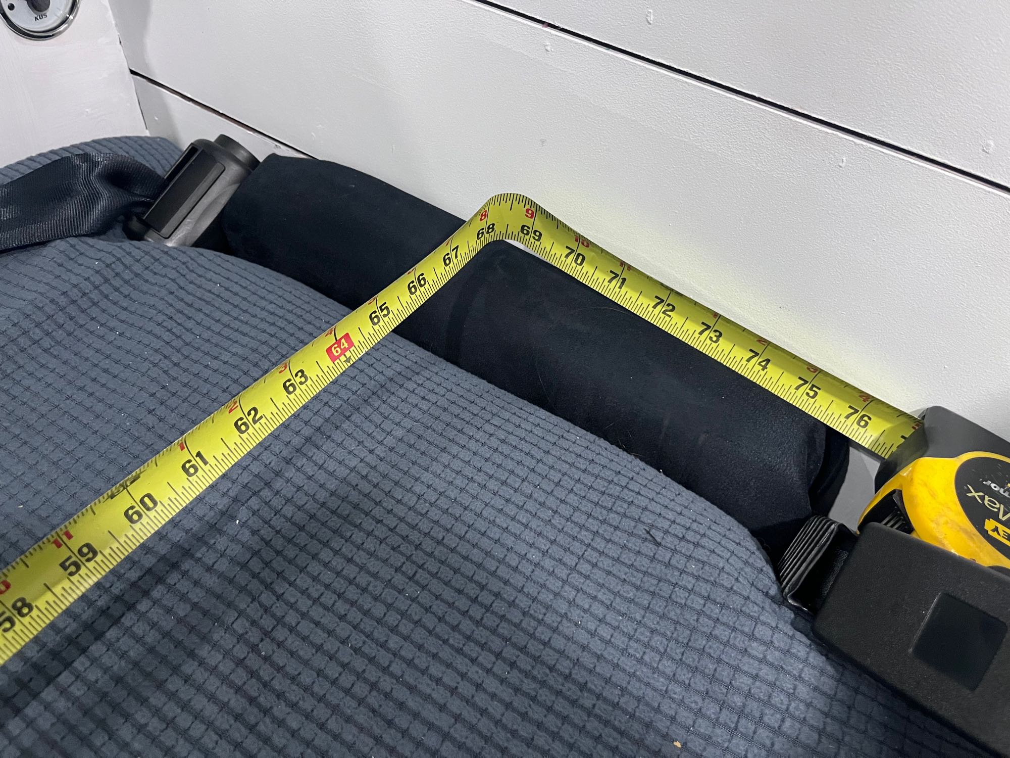 RV rental: Tape measure spanning a dark gray sleeping area, showing a length from approximately 58 to 76 inches. Practical RV space measurement.. Ford Transit 2019