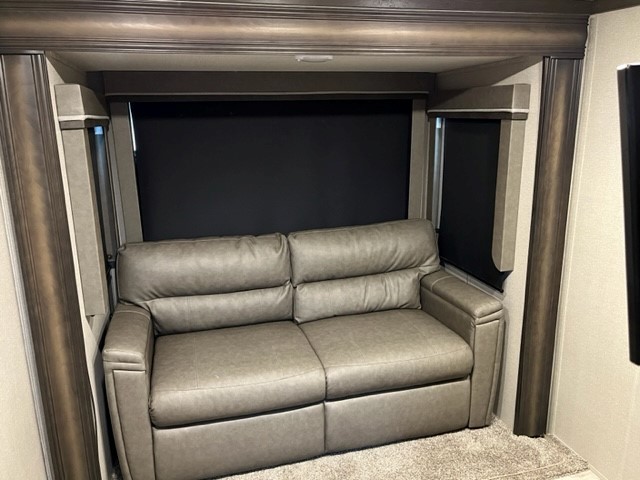 Inside an RV rental: a comfortable gray sofa with blackout shades and detailed wood trim, ready for your travels.. Grand Design Reflection 2020