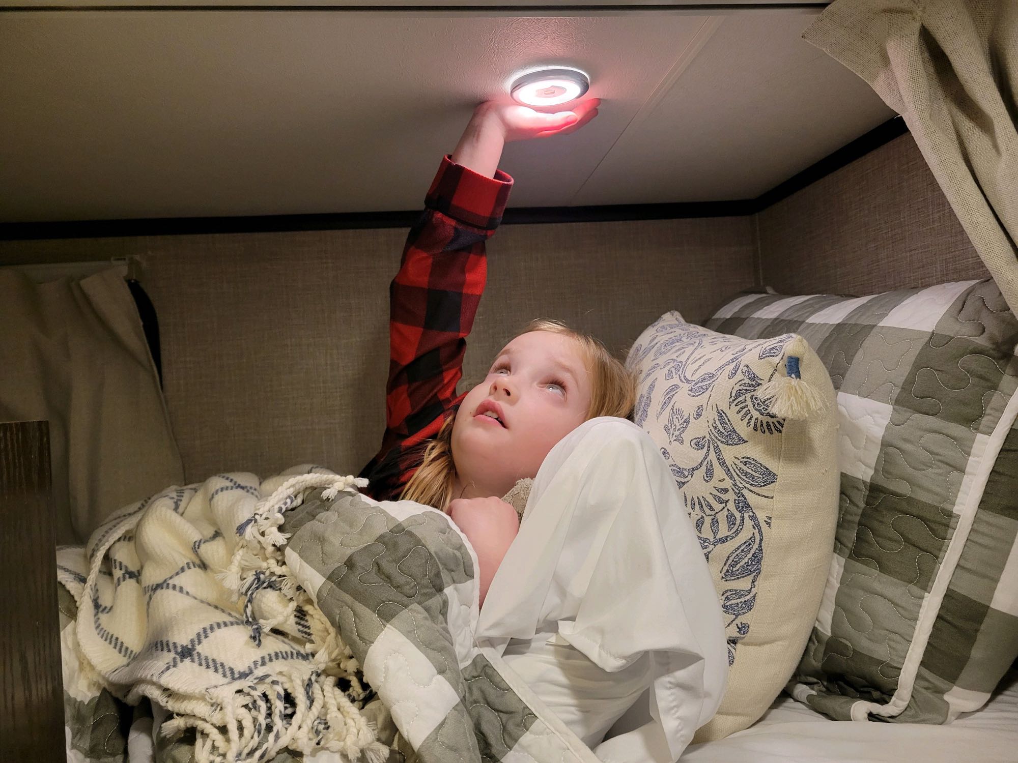 Child in cozy RV rental bunk bed reaches for a red light. A comfortable space for family travel.. Jayco 171BH 2023