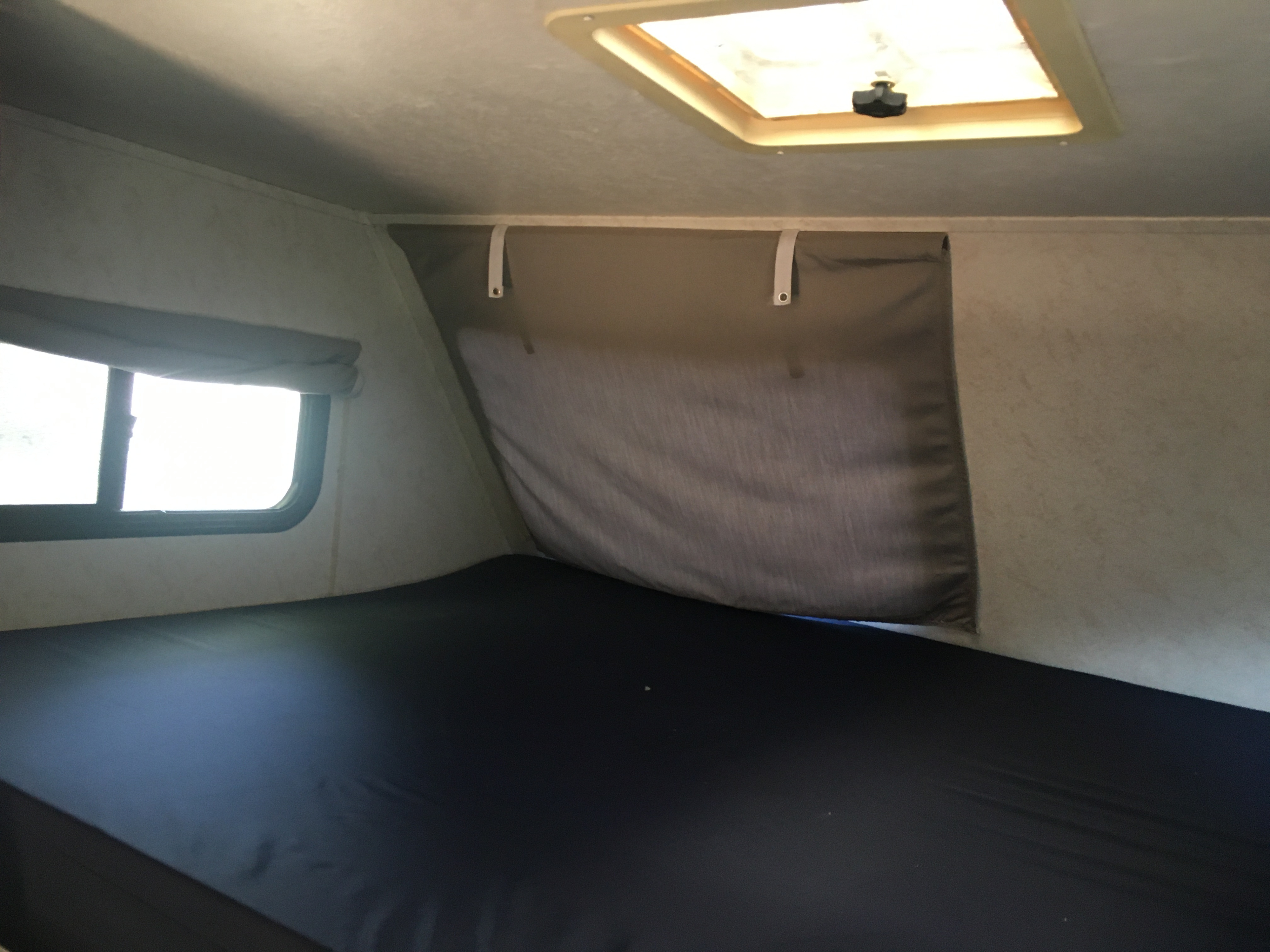 RV rental's comfortable sleeping area with dark mattress, window, and privacy curtain. Ceiling vent overhead.. Four Winds Majestic F350 Super Duty 2003