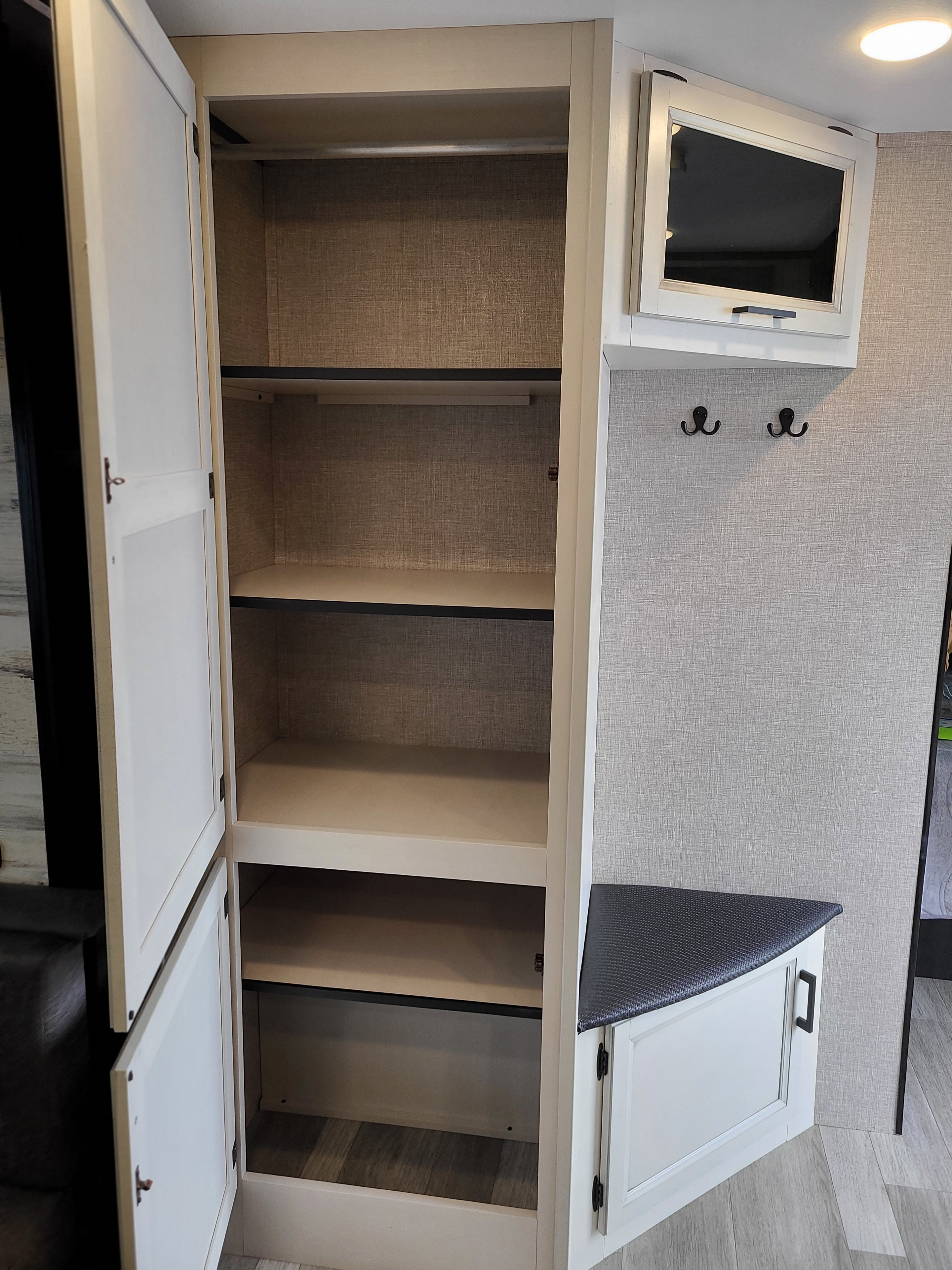 RV rental interior: open tall cabinet with shelves & rod, mounted TV, coat hooks, & lower cabinet.. Jayco Jay Feather 2022