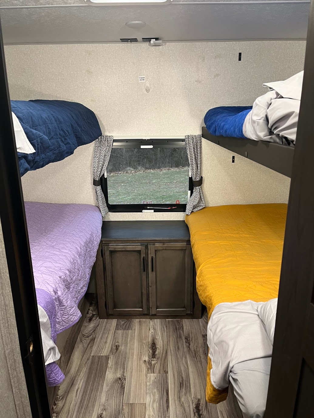 Cozy RV rental interior with four bunk beds and colorful bedding, offering a window view for comfortable travel.. Venture Stratus 2022