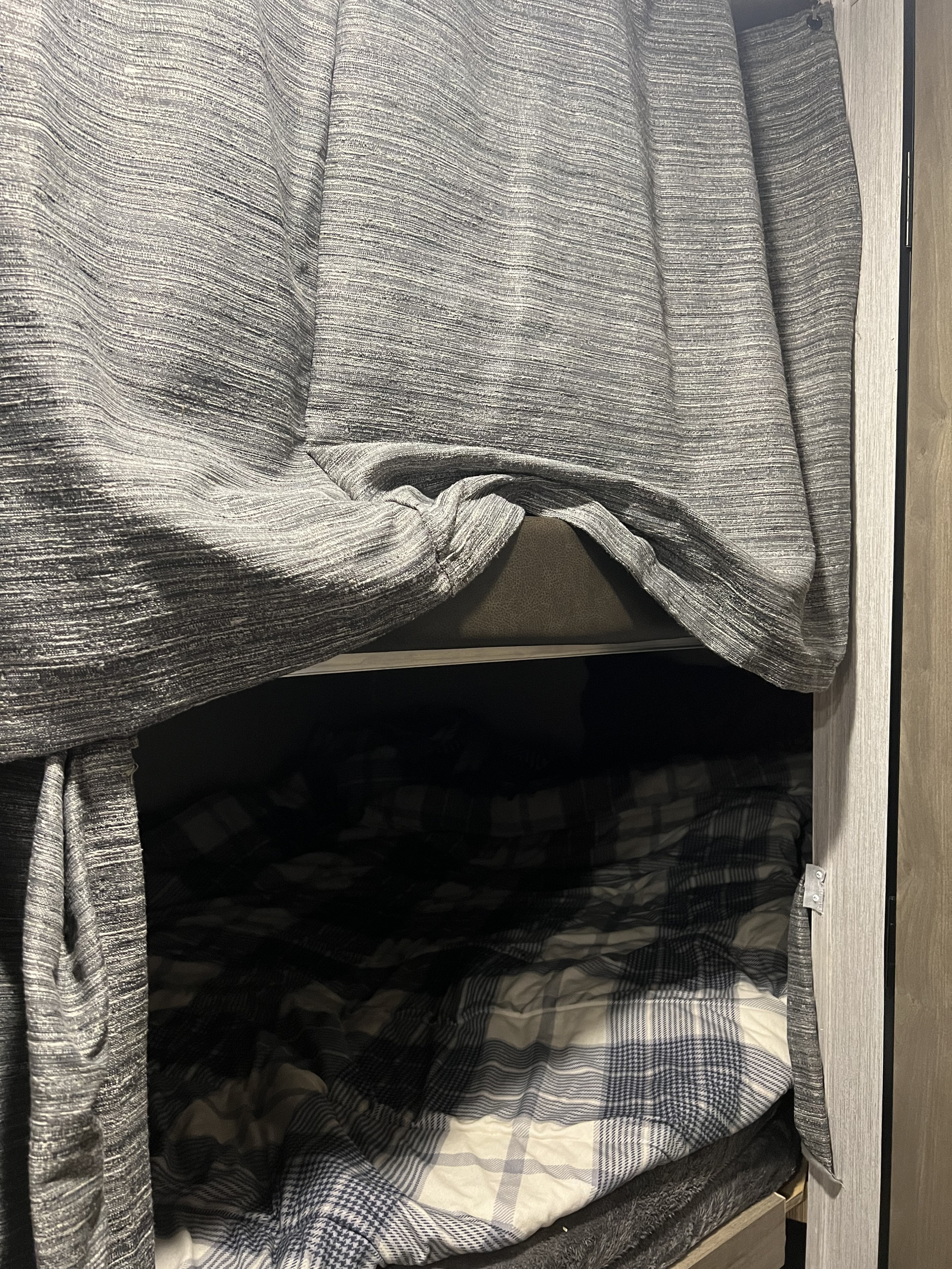 Cozy RV rental bunk bed with plaid bedding and textured privacy curtains.. Forest River Palomino Puma XLE 2022