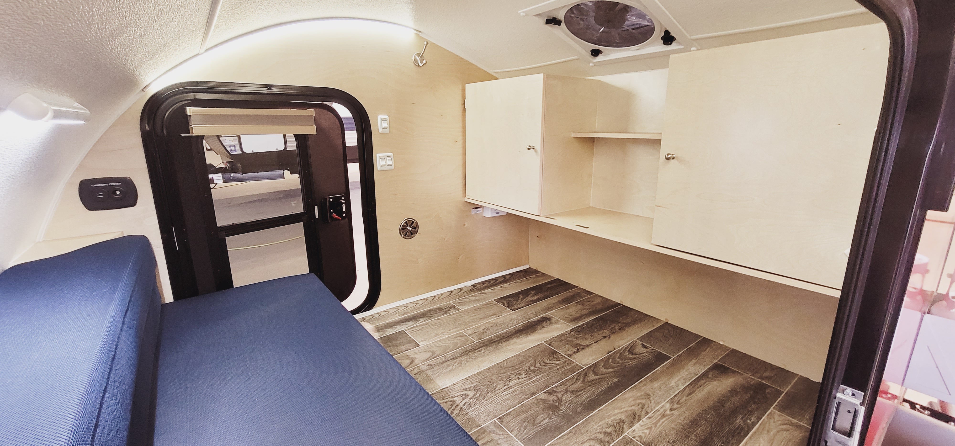 Compact RV rental interior: Features blue bench, wood storage, charging center, and ceiling fan.. Evolve Outing 2020
