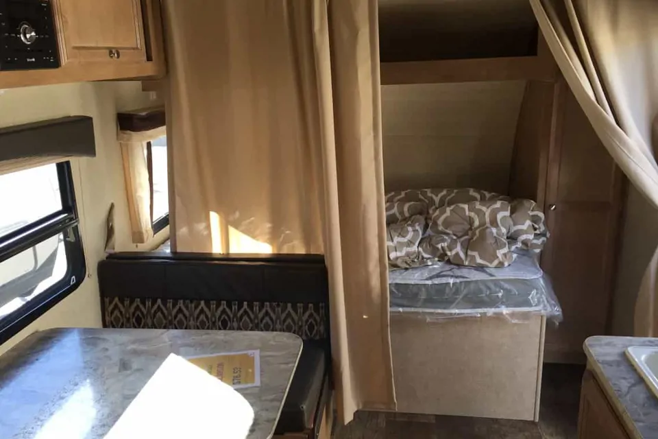 Cozy RV rental interior: dinette, private sleeping area with curtain, and compact kitchen space.. Gulf Stream Other 2018