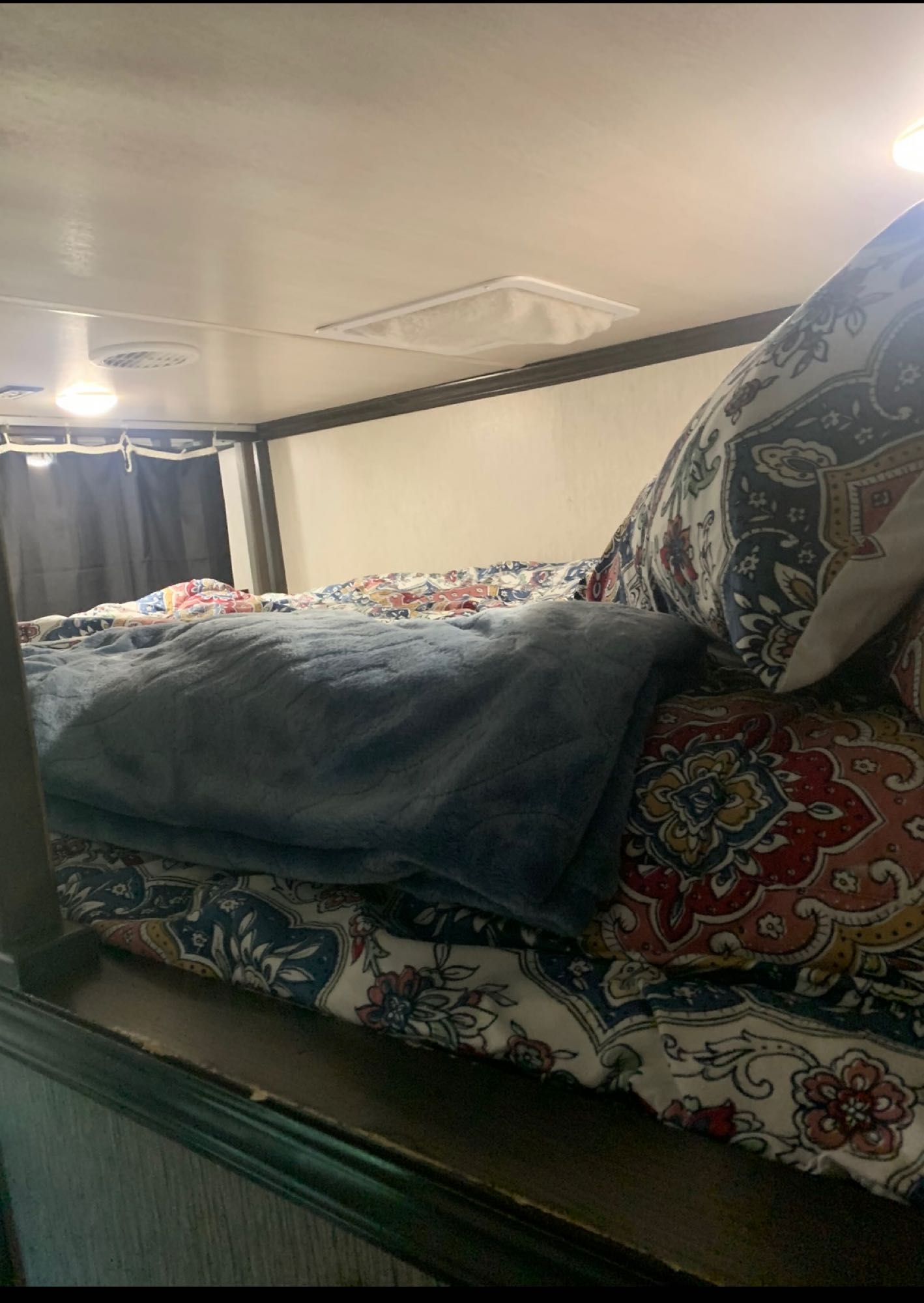 Cozy bunk bed interior in an RV rental, featuring colorful patterned bedding and a plush blue blanket for comfortable travel.. Heartland Elkridge 2019