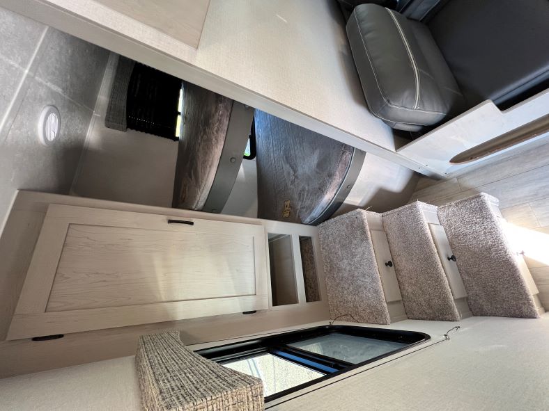 Explore this RV rental's compact interior: bunk bed, cabinet, and carpeted stairs to a cushioned upper bed/lounge.. Coachmen Clipper 262 BH C 2023