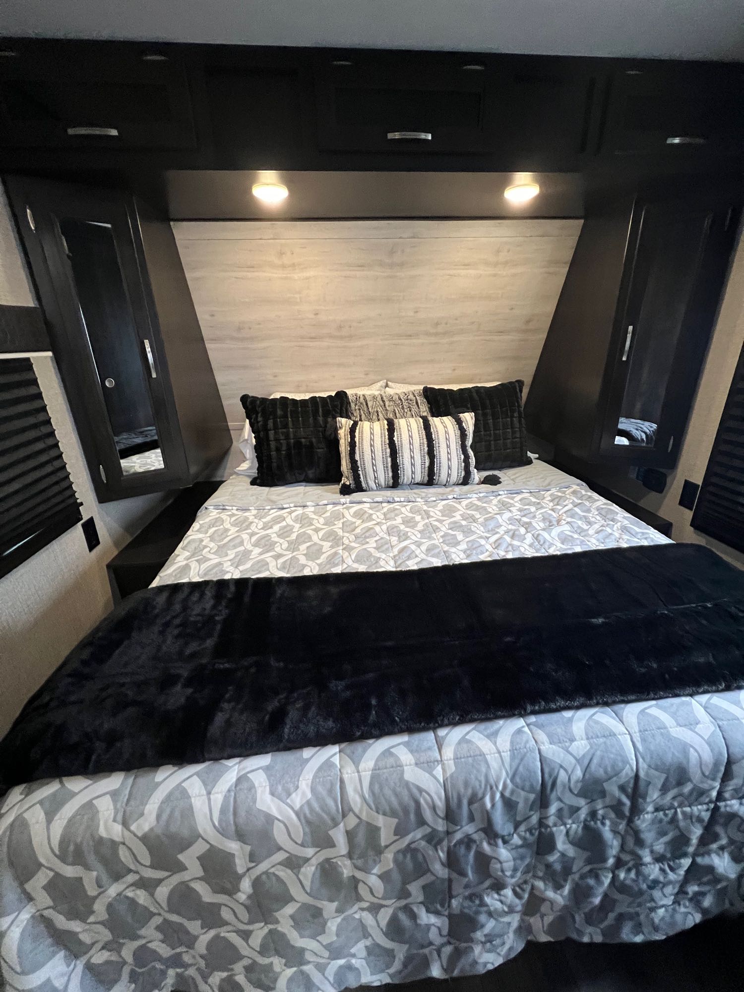 Cozy RV rental bedroom with patterned bedding, black throw, and compact overhead storage.. Jayco Jay Flight 2021