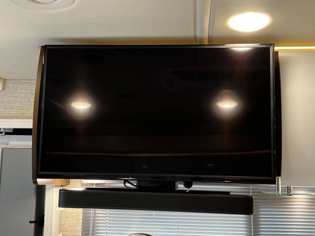 Compact RV rental: wall-mounted TV with a soundbar, ready for entertainment on the road.. Winnebago Navion 2021