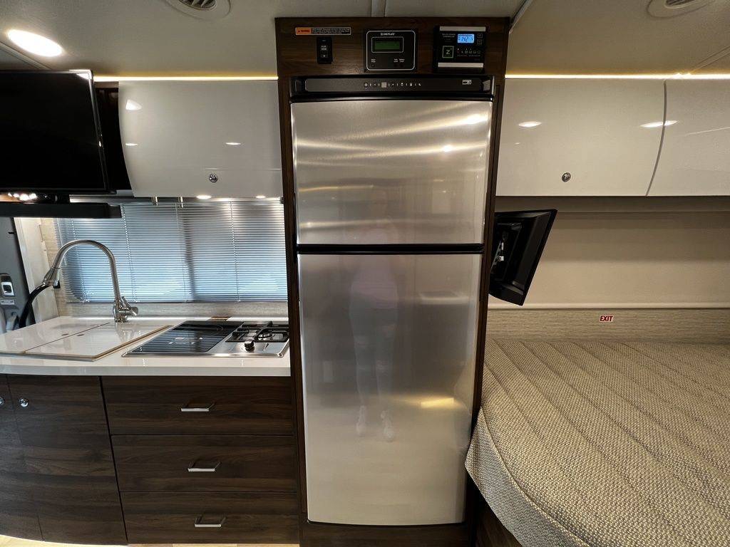 Spacious RV rental interior featuring a kitchen with stove, sink, large refrigerator, and comfortable sleeping space.. Winnebago View 2023