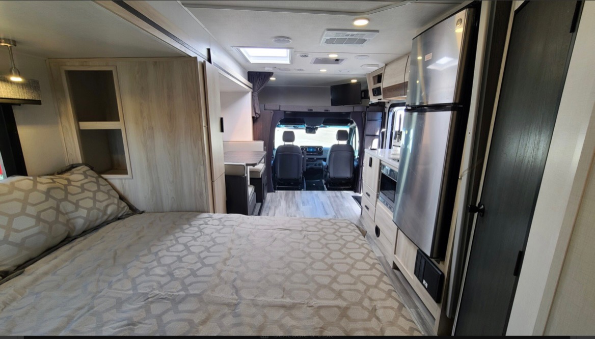Looking forward in a modern **rv rental**, from the bed to the kitchen, dinette, and front cockpit area.. Forest River Forester 2023