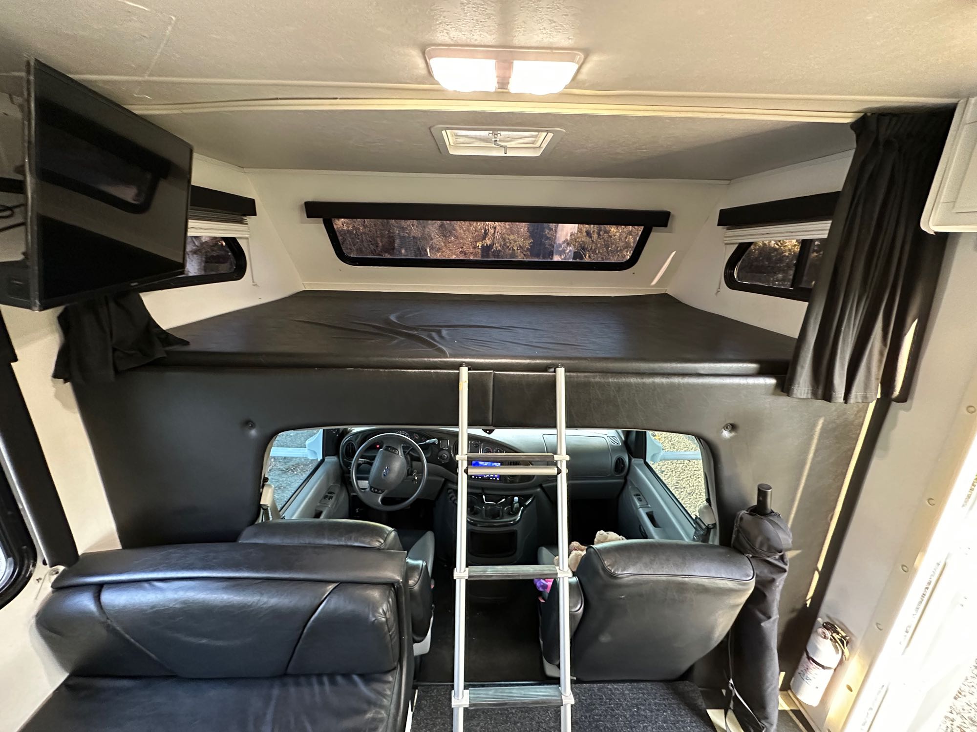 Spacious RV rental interior: over-cab bunk, ladder for access, TV, and cozy cab area for your next adventure.. Four Winds Fun Mover 2004