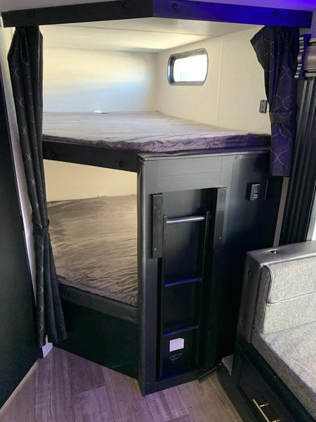 Explore this RV rental's cozy bunk beds. Features integrated ladder, window, and curtain for compact sleeping.. Forest River Grey Wolf 26DBH 2022