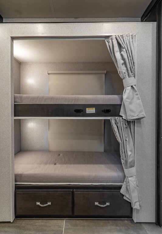 Inside this **rv rental**, bunk beds with integrated storage, blinds, and curtains offer cozy sleeping for travelers.. Thor Motor Coach Venetian 2023