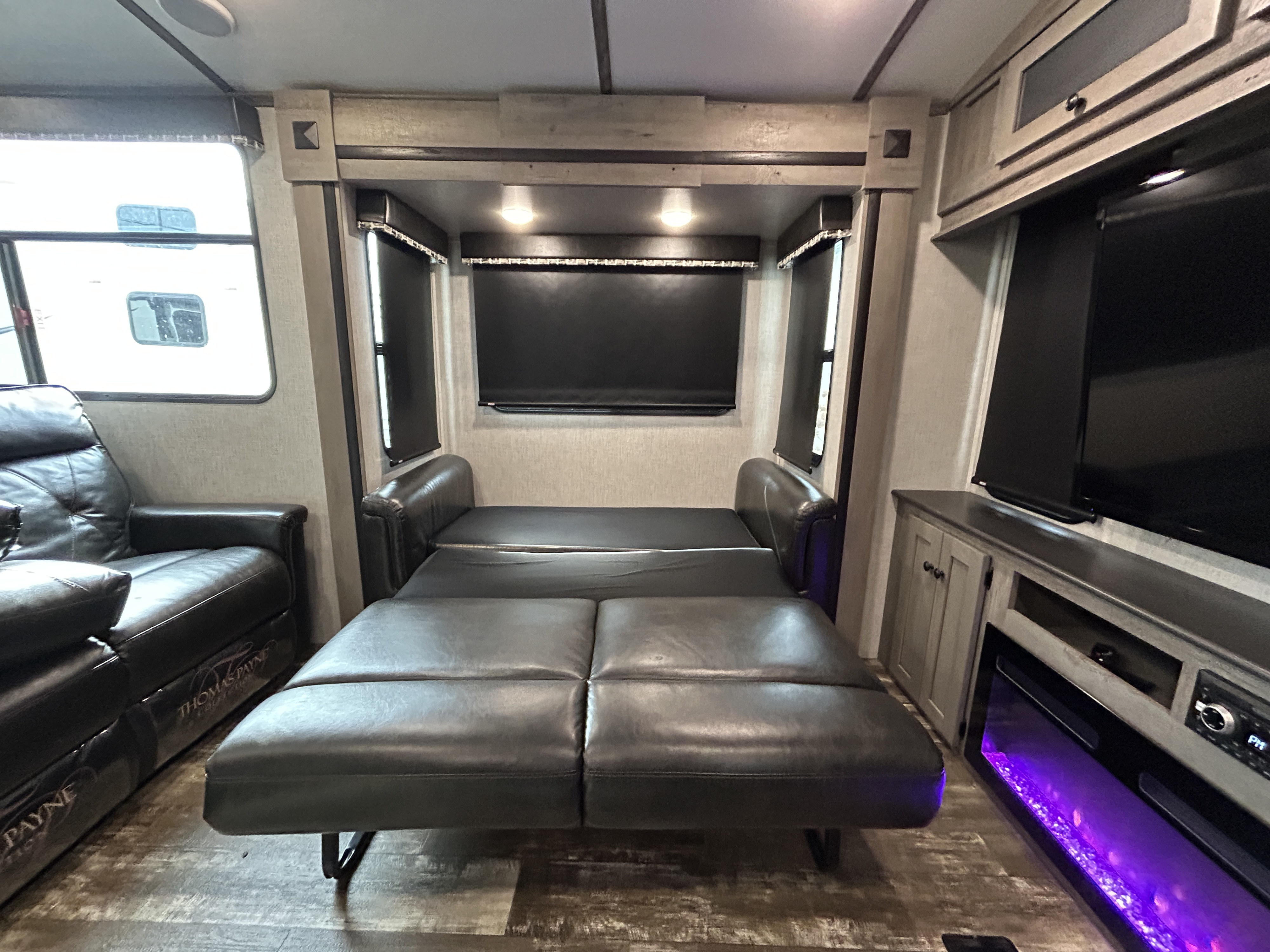 RV rental interior: A dark leather sofa unfolds into a bed, alongside recliners, and an entertainment center with a fireplace.. Keystone Outback 2020