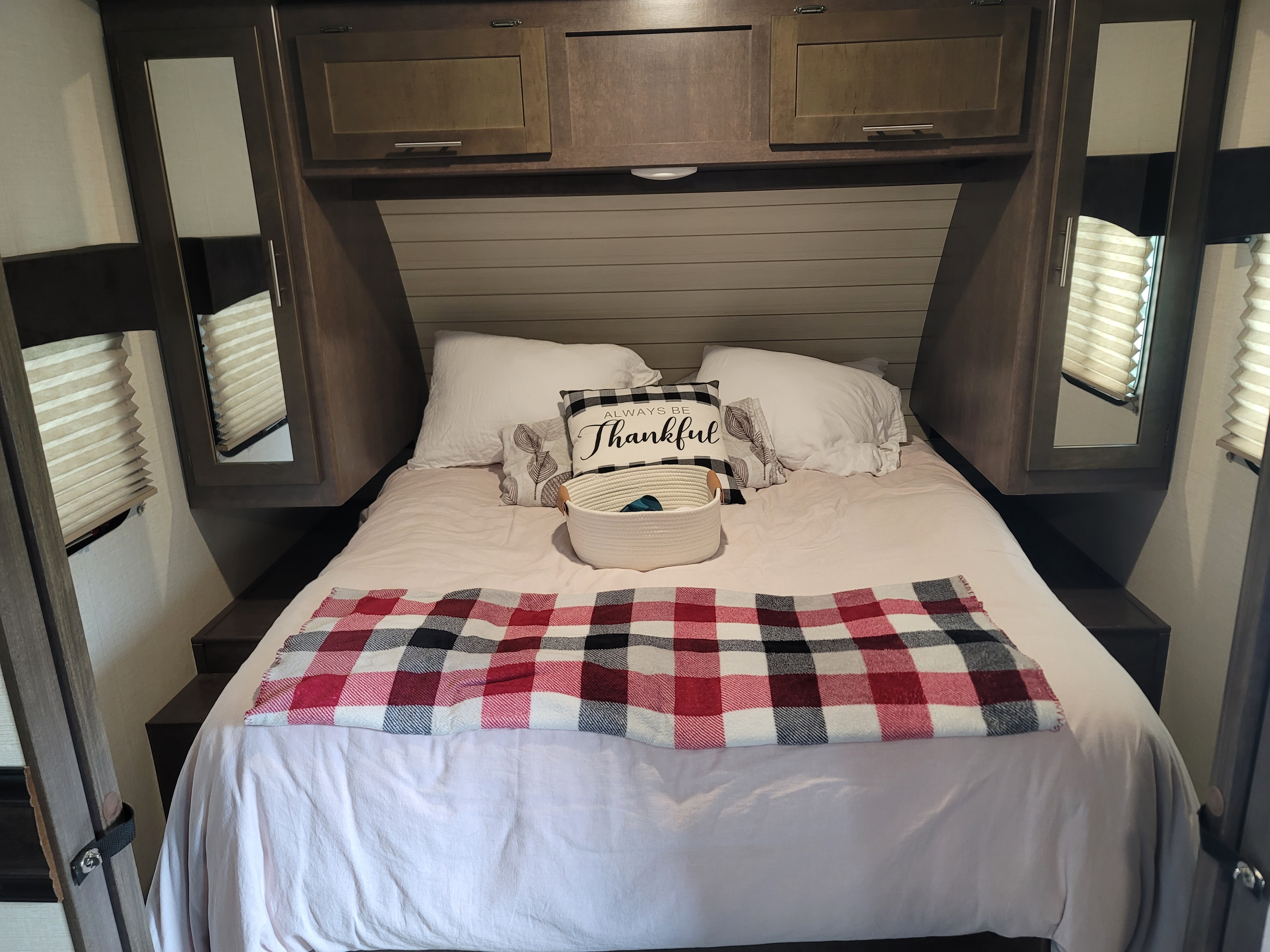 Step into comfort with this RV rental bedroom: soft bed, plaid blanket, "Thankful" pillow, and built-in storage.. Crossroads RV Sunset Trail Super Lite 2018
