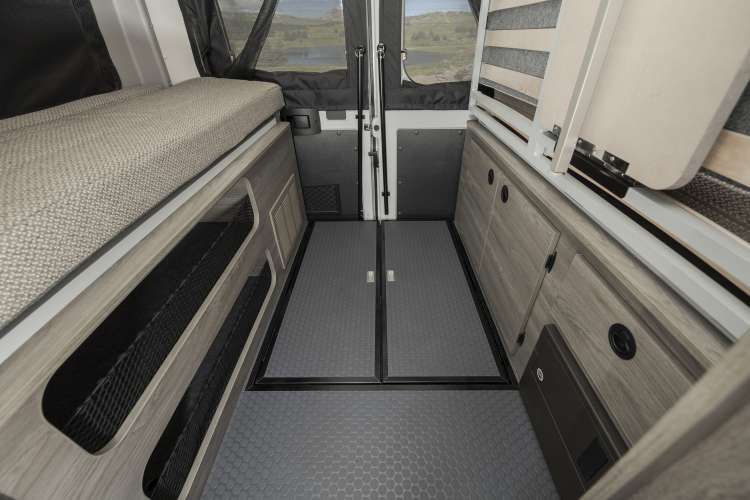 Compact camper van RV rental interior: bed, storage, cabinets, and rear doors to a scenic view.. Winnebago Solis PX 2023